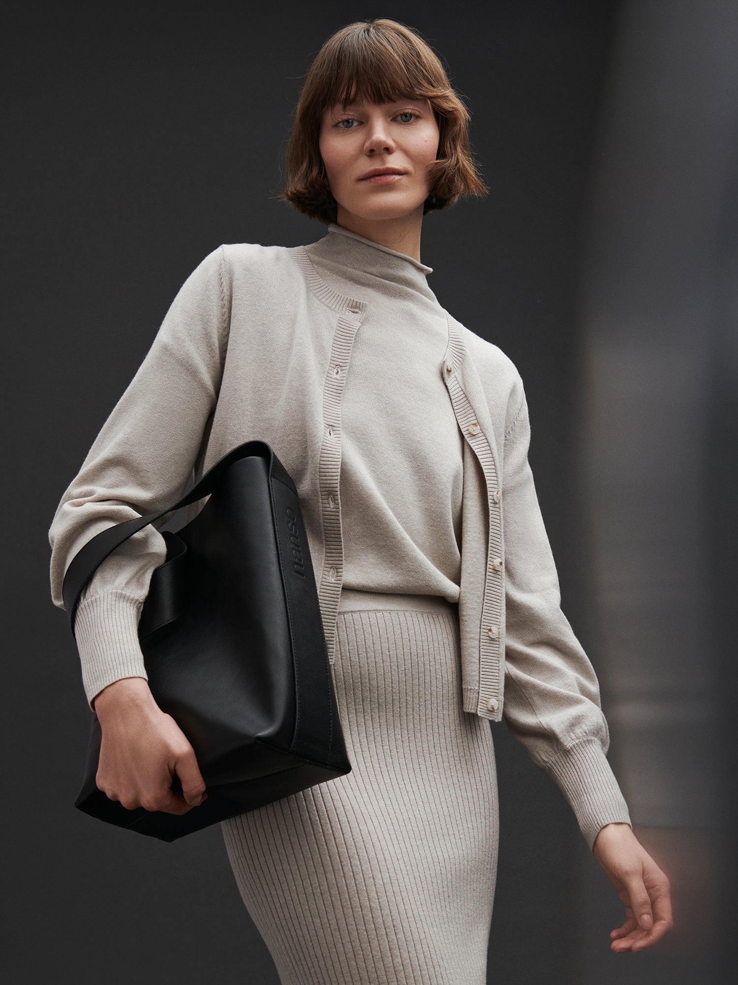 Nanson naisten tyylikäs musta OLKA -nahkalaukku mallin päällä edestä. Olkalaukussa on magneettinappikiinnitys, olkahihna ja hopeansävyiset metalliosat.