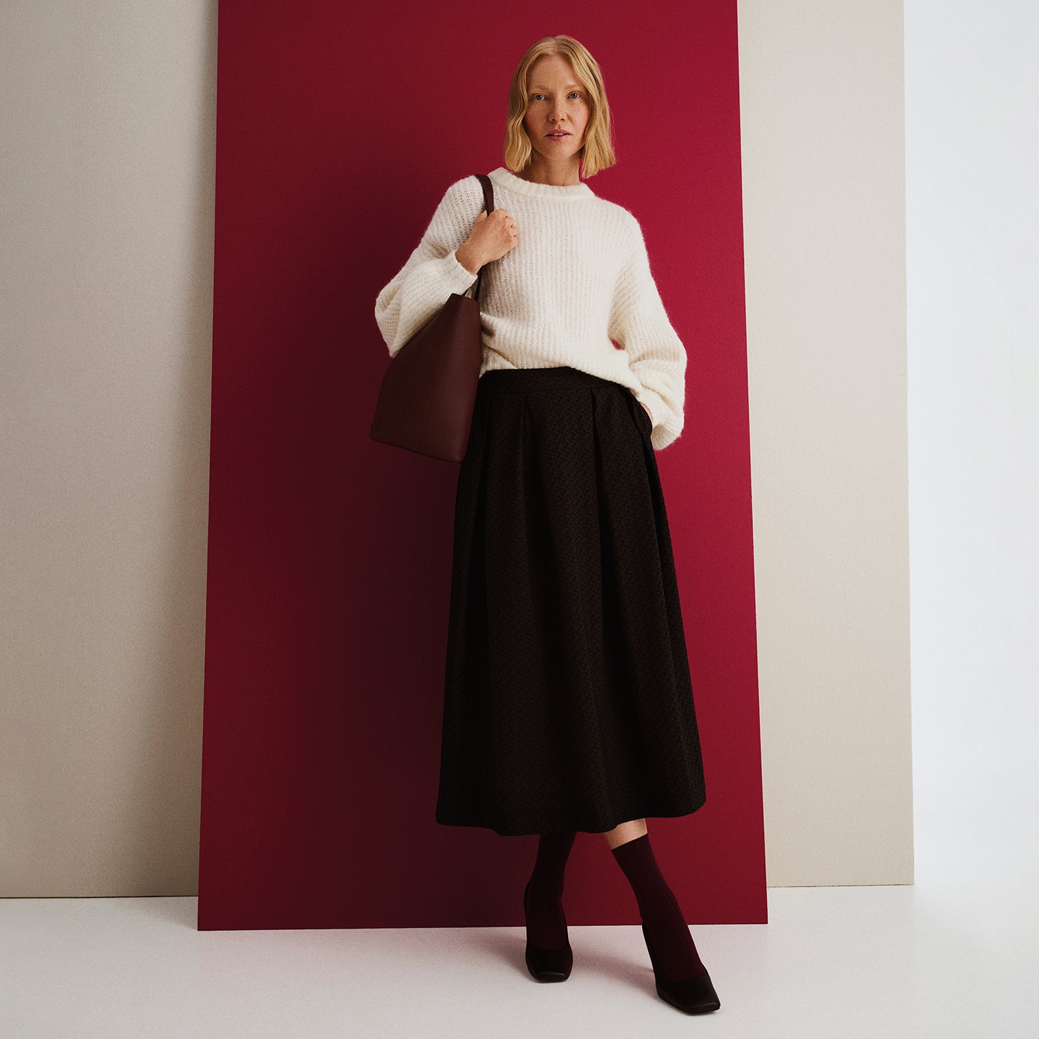 Nanson naisten luonnonvalkoinen Karamelli neulepusero yhdistettynä mustaan Reliefi hameeseen ja viininpunaiseen Maxi Naru nahkalaukkuun, mallin päällä.