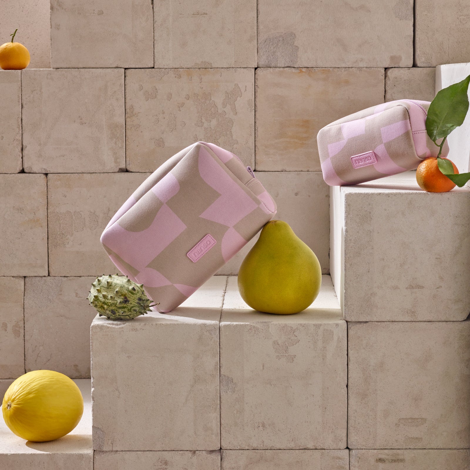 Nanson Kallio -kosmetiikkalaukut kauniissa asetelmassa hedelmien kanssa.