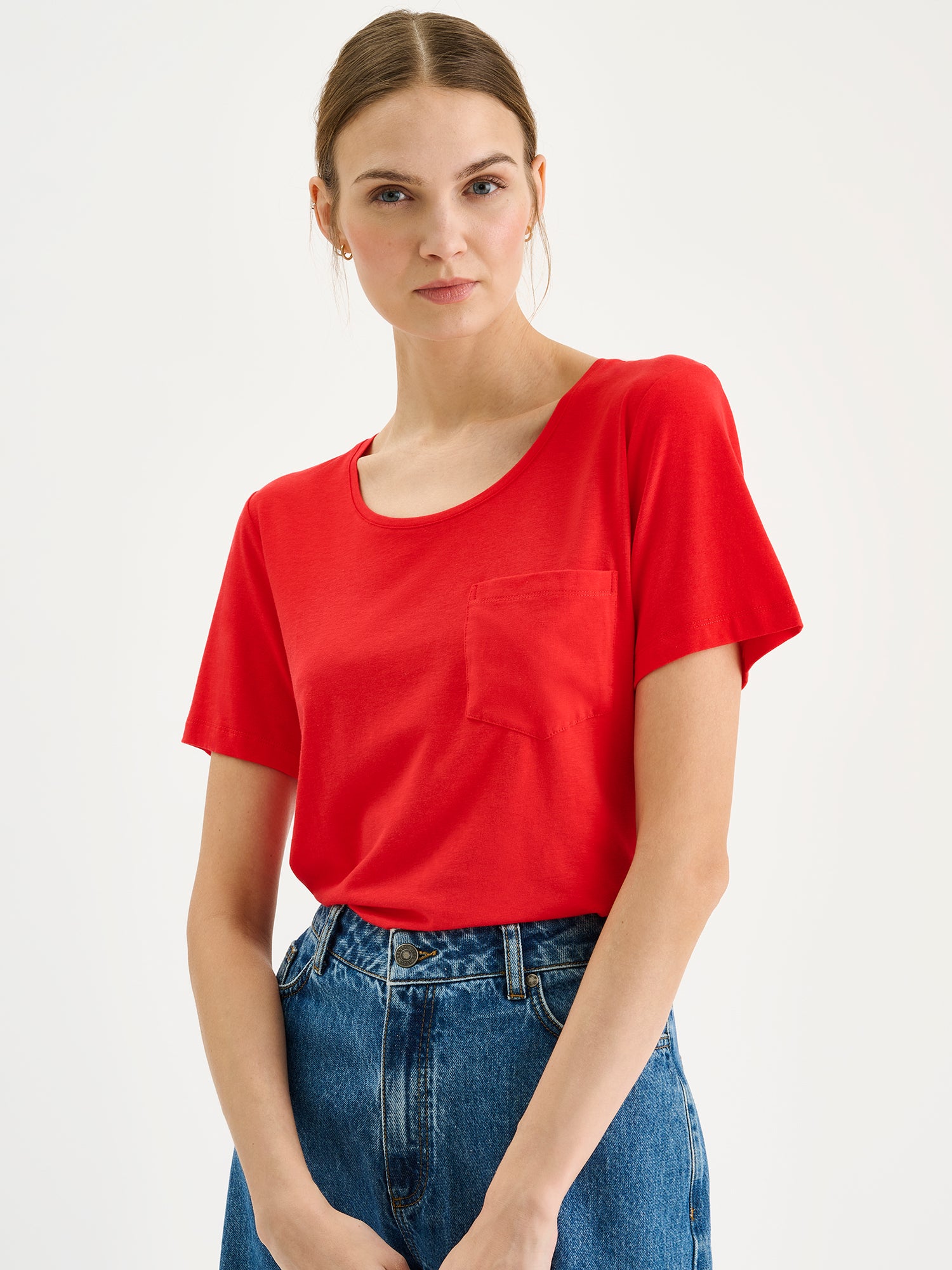 Nanson naisten punainen Tasku-t-paita pyöreällä pääntiellä mallin päällä farkkushortsien kanssa lähikuvassa.