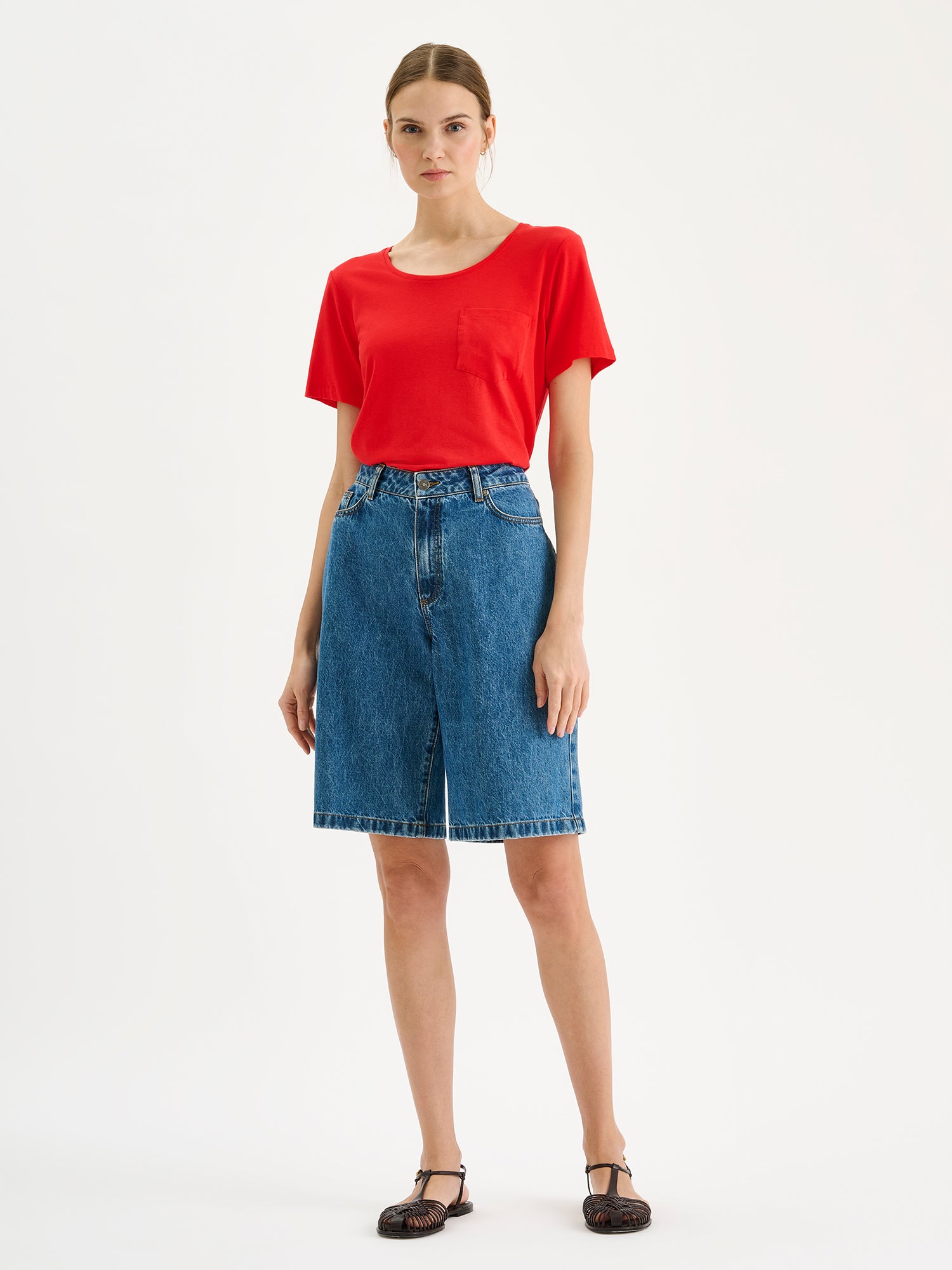 Nanson naisten punainen Tasku-t-paita pyöreällä pääntiellä mallin päällä farkkushortsien kanssa.