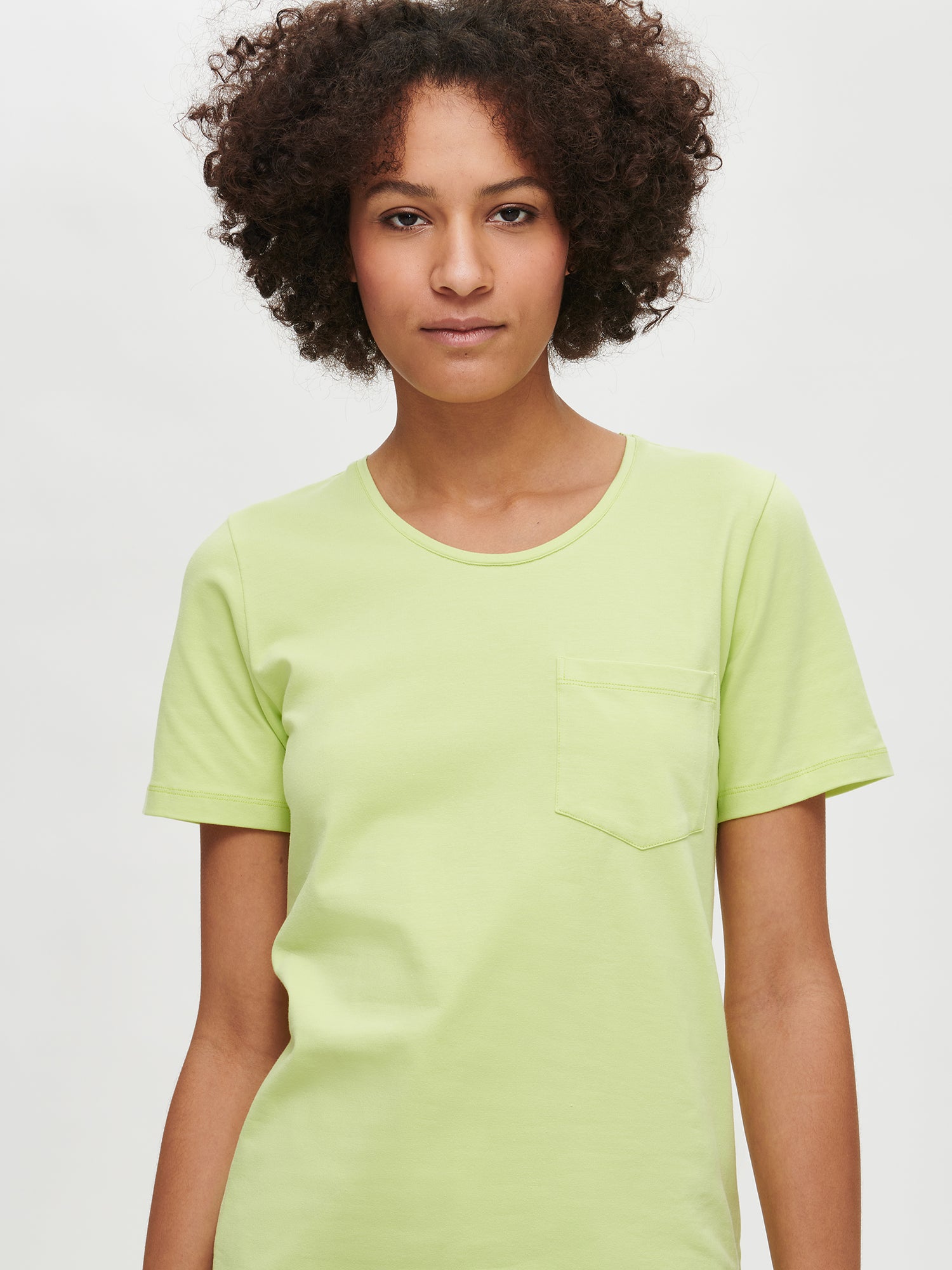 Nanson naisten limenvihreä Tasku-t-paita pyöreällä pääntiellä ja rintataskulla lähikuvassa mallin päällä.