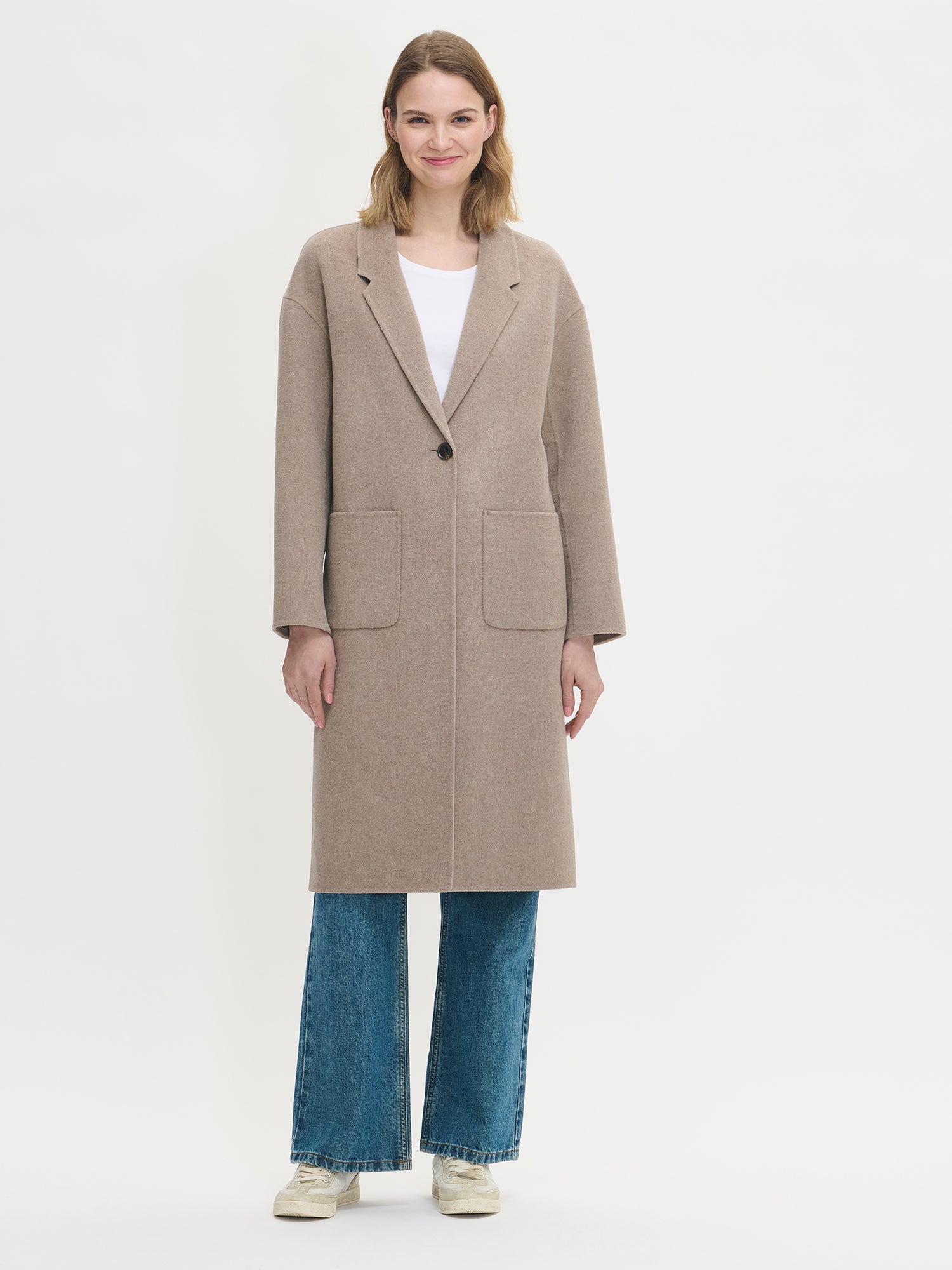 Nanson naisten tyylikäs ja klassinen beige Ylle-villakangastakki. Mallilla edestä kiinni.