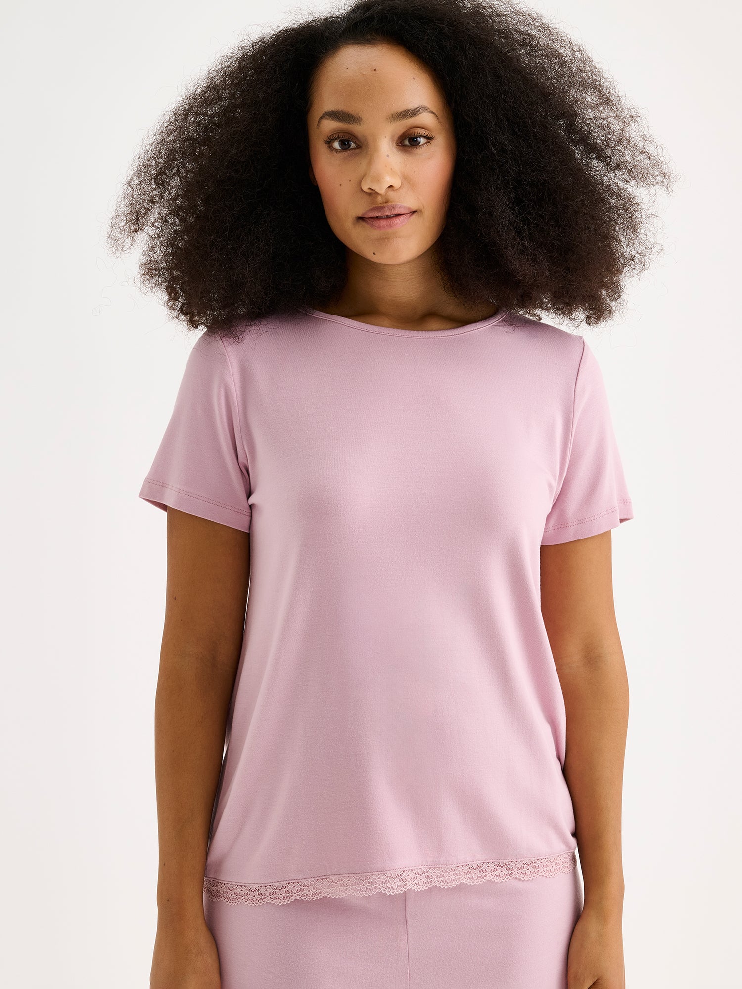 Naisten ylellisen pehmeä vaaleanpunainen Pitsi-pusero lyhyillä hihoilla mallin päällä Pitsi -shortsien kanssa, läheltä kuvattuna.