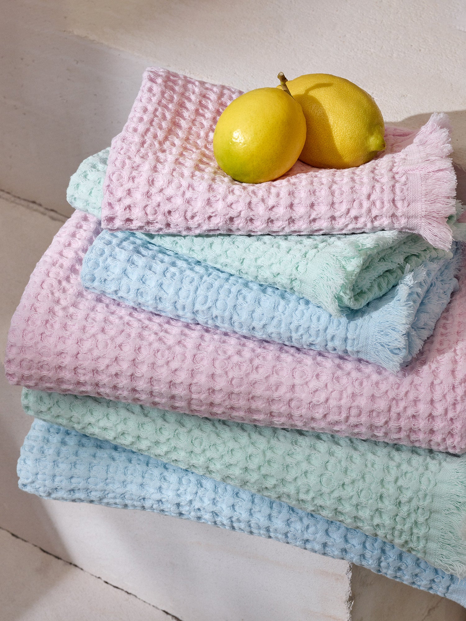 Nanson pastellisävyiset Vohveli-pyyhkeet pinossa hedelmien kanssa.