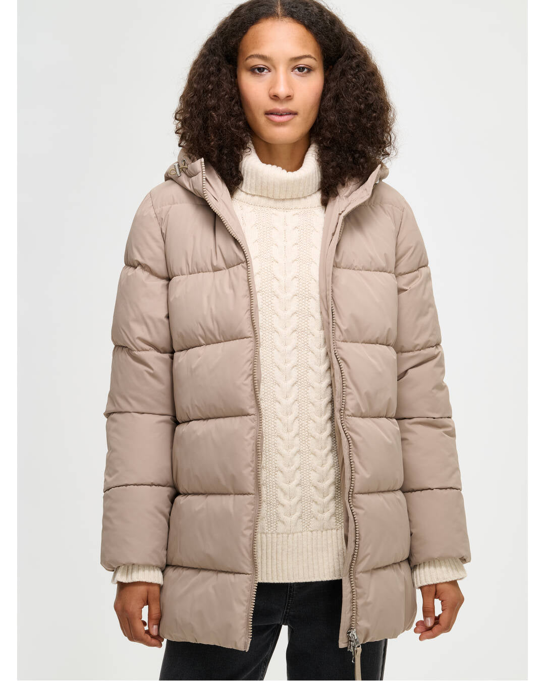 Lämmin ja muhkea beige Lumi-toppatakki miellyttävän kevyellä vanuvuorella. Mallin päällä edestä läheltä kuvattuna ja takki auki.