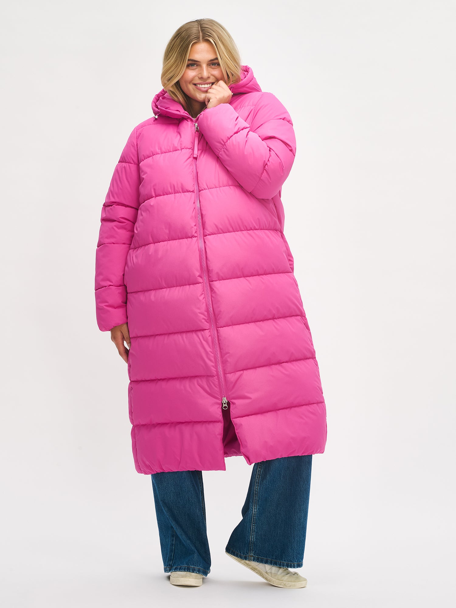 Lämmin ja muhkea pitkä pinkki Lumi-toppatakki miellyttävän kevyellä vanuvuorella. Mallin päällä edestä, kiinni.