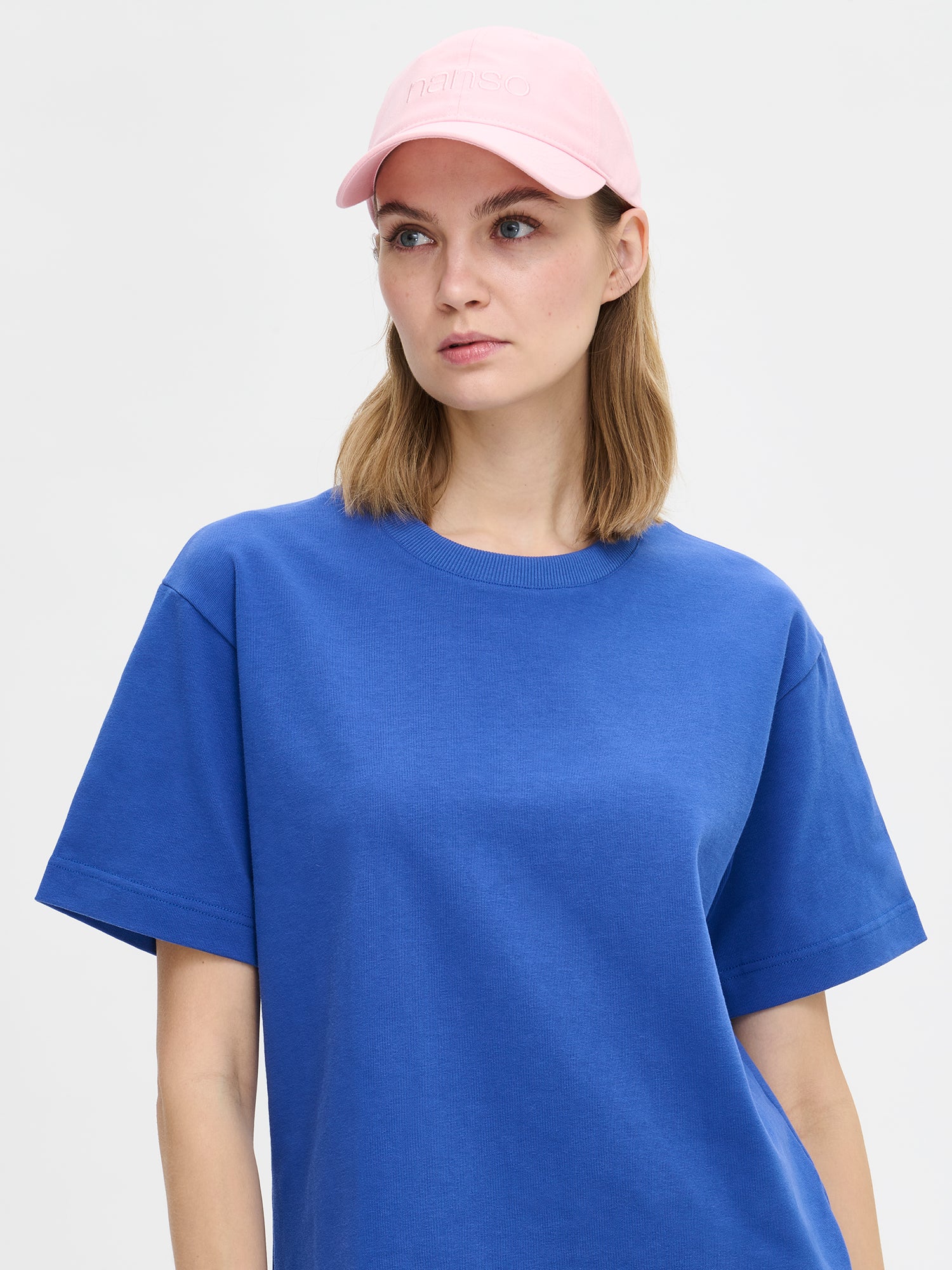 Nanson naisten tyylikäs vaaleanpunainen Logo-lippalakki mallin päällä sinisen T-paidan kanssa.