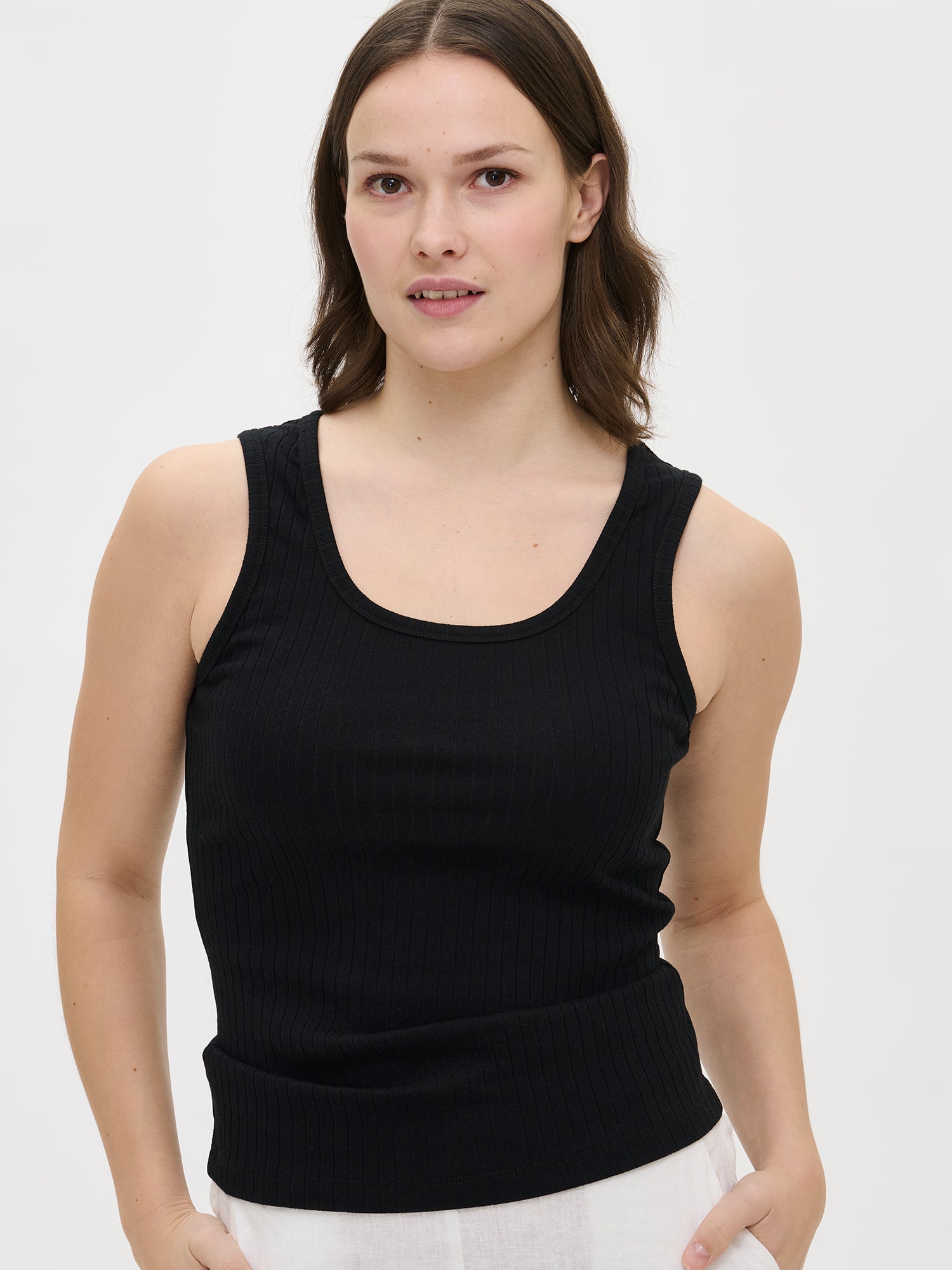 Nanson naisten ajaton musta hihaton Seri-toppi pyöreällä pääntiellä ja suoralla, lantiolle ulottuvalla helmalla, mallin yllä edestä lähikuvassa.