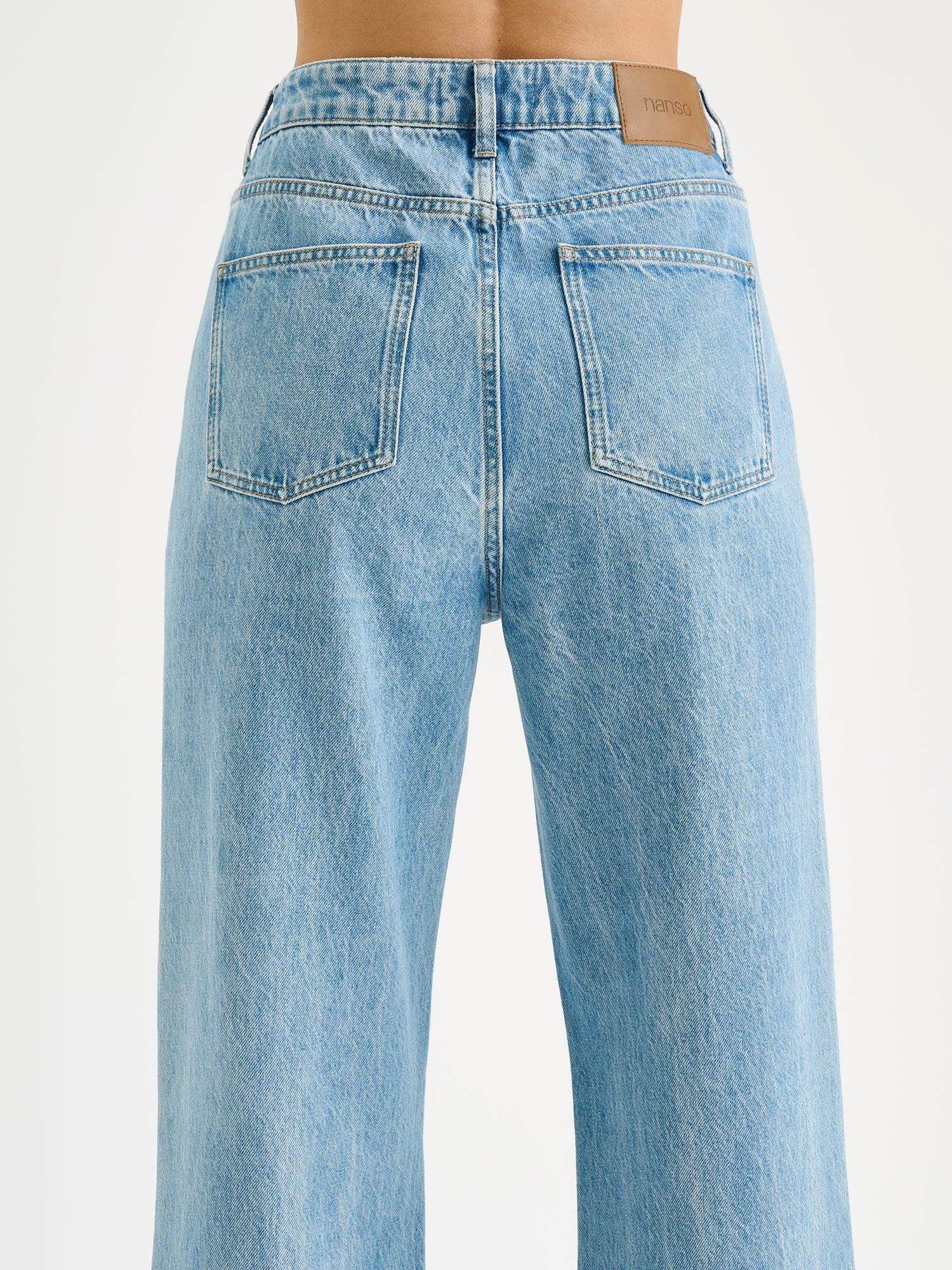 Nanson naisten vaaleansiniset leveälahkeiset Levee-farkut korkealla vyötäröllä mallin päällä lähikuvassa takaa kuvattuna.