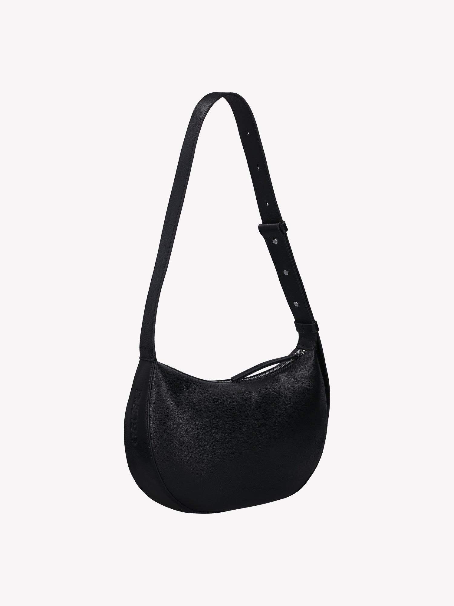 Tyylikäs ja trendikäs puolikuun mallinen musta OLKA KUU - nahkalaukku. Laukussa on olalle sopiva kantohihna ja logo nahan pinnassa. Vuoritetussa laukussa on päällä metallinen vetoketju. Tuotekuva mustasta laukusta takaa.