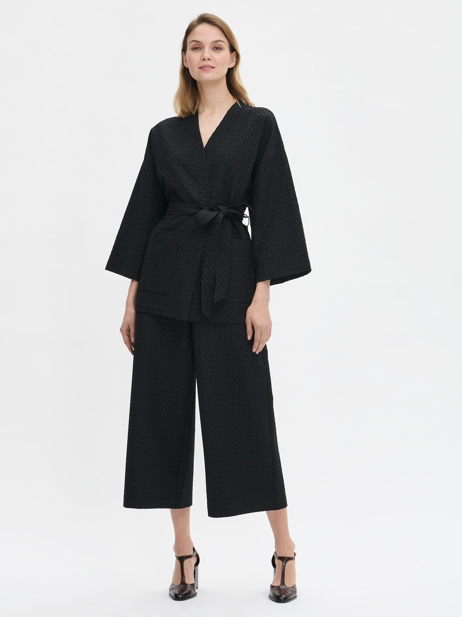 Nanson naisten musta Reliefi-takki kauniilla struktuuripinnalla ja vyöllä mallin päällä edestä