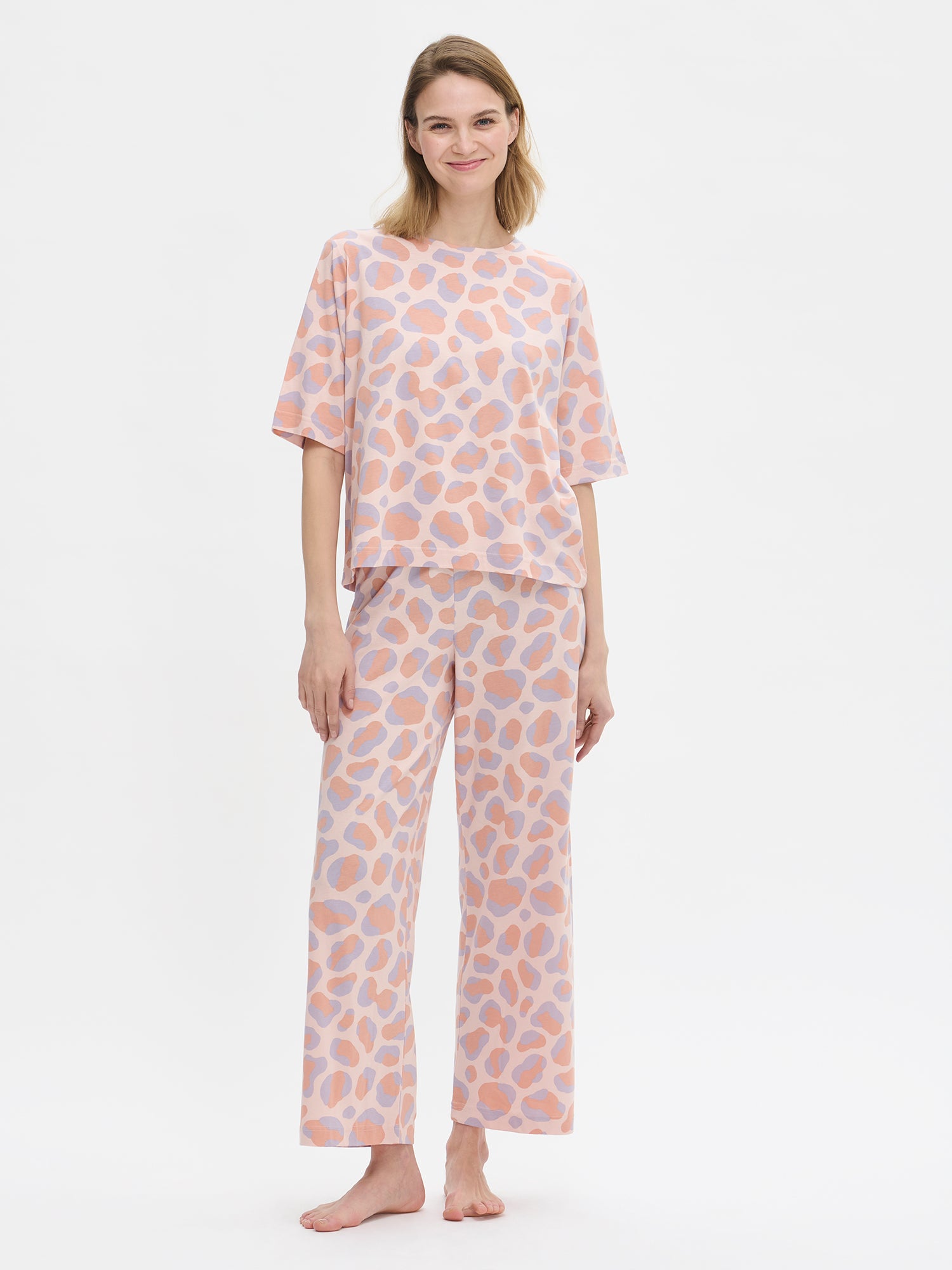 Nanson naisten Pantteri-loungewear-asu, jossa vaaleanpunainen Pantteri-T-paita ja yhteensopivat housut. Helma asettuu lantiolle. Mallin päällä kokovartalokuvassa edestä.