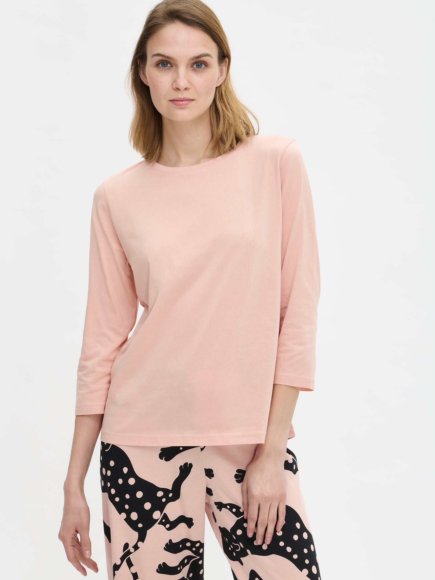 Nanson naisten vaaleanpunainen Leonora-pyjama, mallin yllä läheltä edestä. Kuvassa näkyy puseron pääntie ja housujen kuosi.
