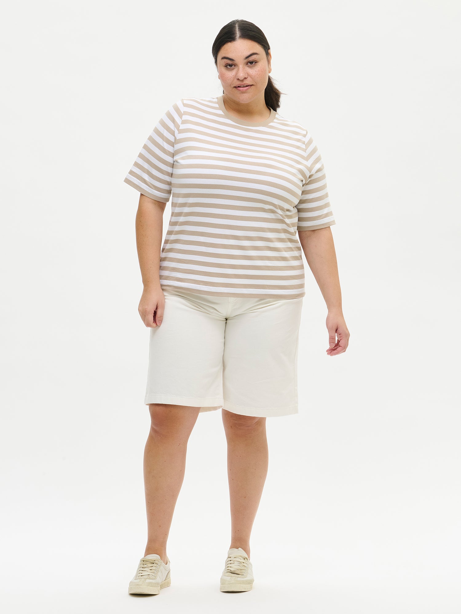 Nanson naisten mukavat rennosti istuvat luonnonvalkoiset Levee-shortsit farkkumateriaalista vyötärökaitaleella, jossa edessä vetoketju ja polviin asti ulottuvat levenevät lahkeet Plus size -mallin yllä edestä.