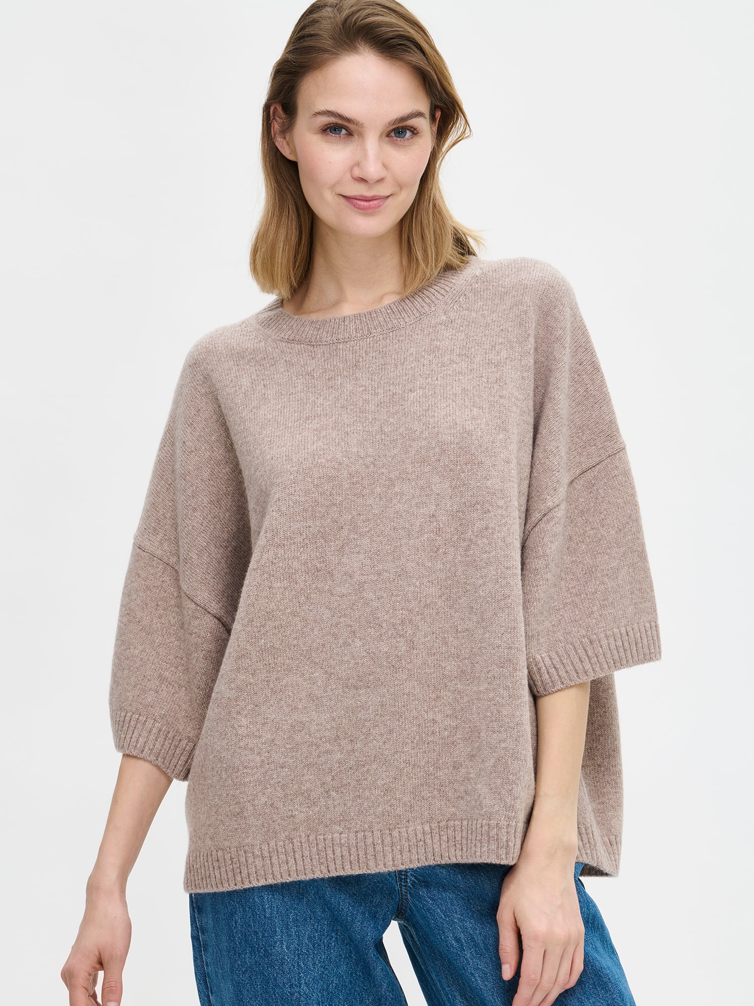 Naisten rento Oversize-tyylinen harmaanbeige Lana-neulepaita, jossa pyöreä resoripääntie, 1/2 pituiset hihat ja ribbineulos hihansuissa ja helmassa. Kuvassa mallin päällä farkkujen kanssa, läheltä kuvattuna.