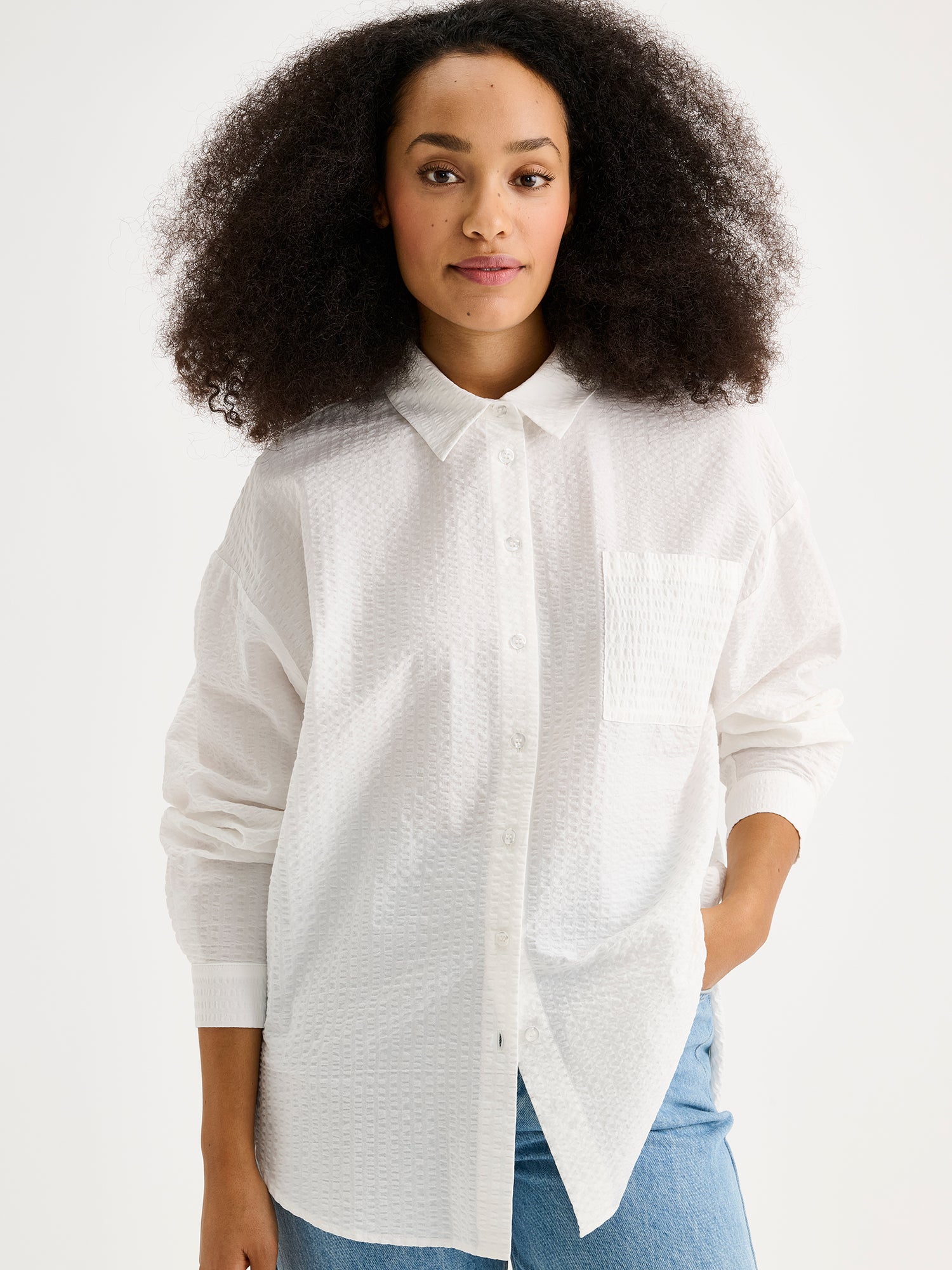 Nanson naisten tyylikäs sininen Maari-paitapusero, jossa kaulus, pudotettu olkalinja, rintatasku ja napit edessä. Kevyessä kudotussa materiaalissa on kaunis pintastruktuuri. Kuvassa mallin päällä, läheltä kuvattuna.