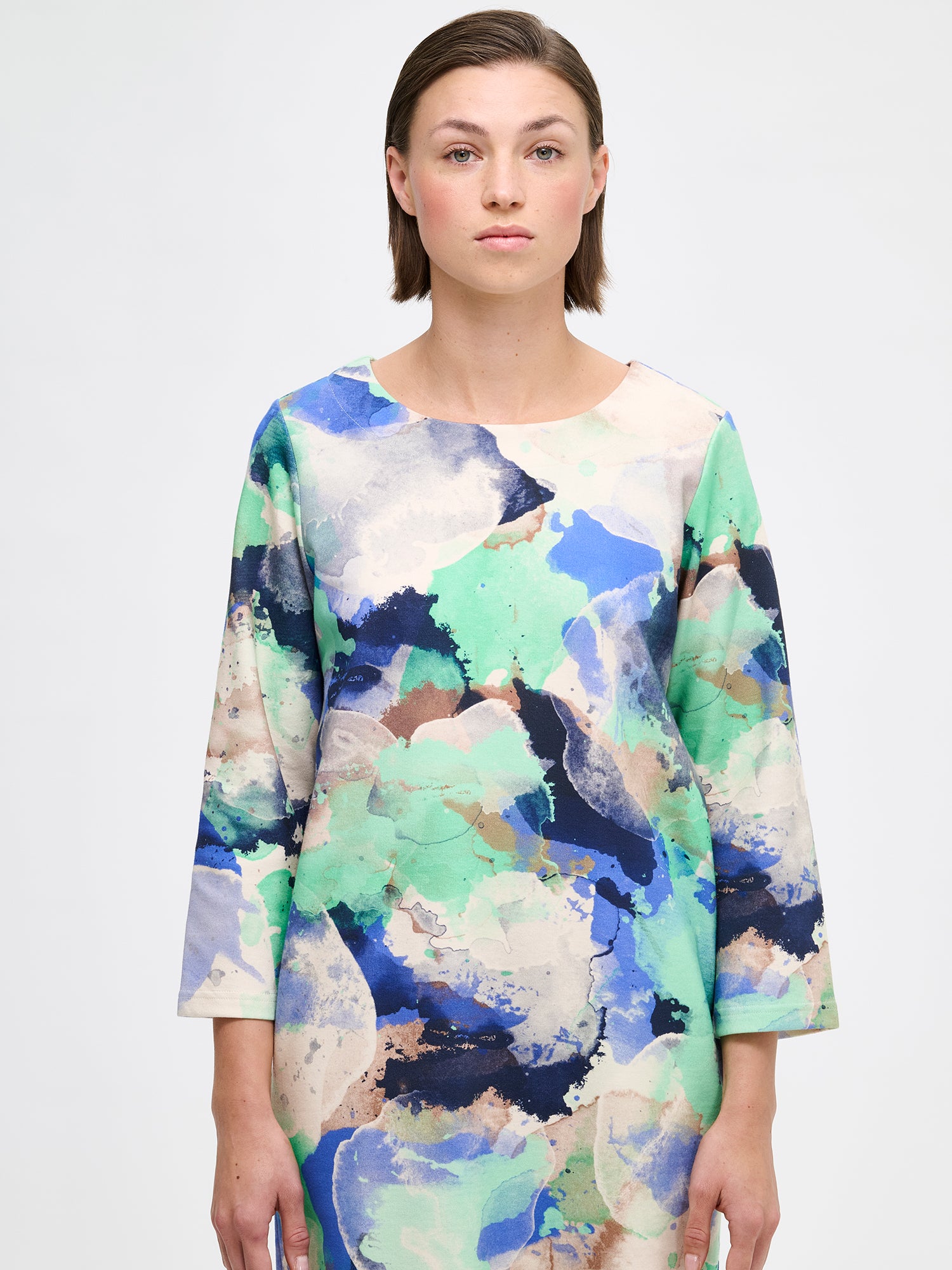 Naisten Sirius-mekko näyttävällä abstraktilla kuosilla on malliltaan suoralinjainen ja pelkistetty. Käytännöllisessä mekossa on myös taskut ja 3/4 hihat. Mallin päällä kuvattuna edestä, lähikuva.