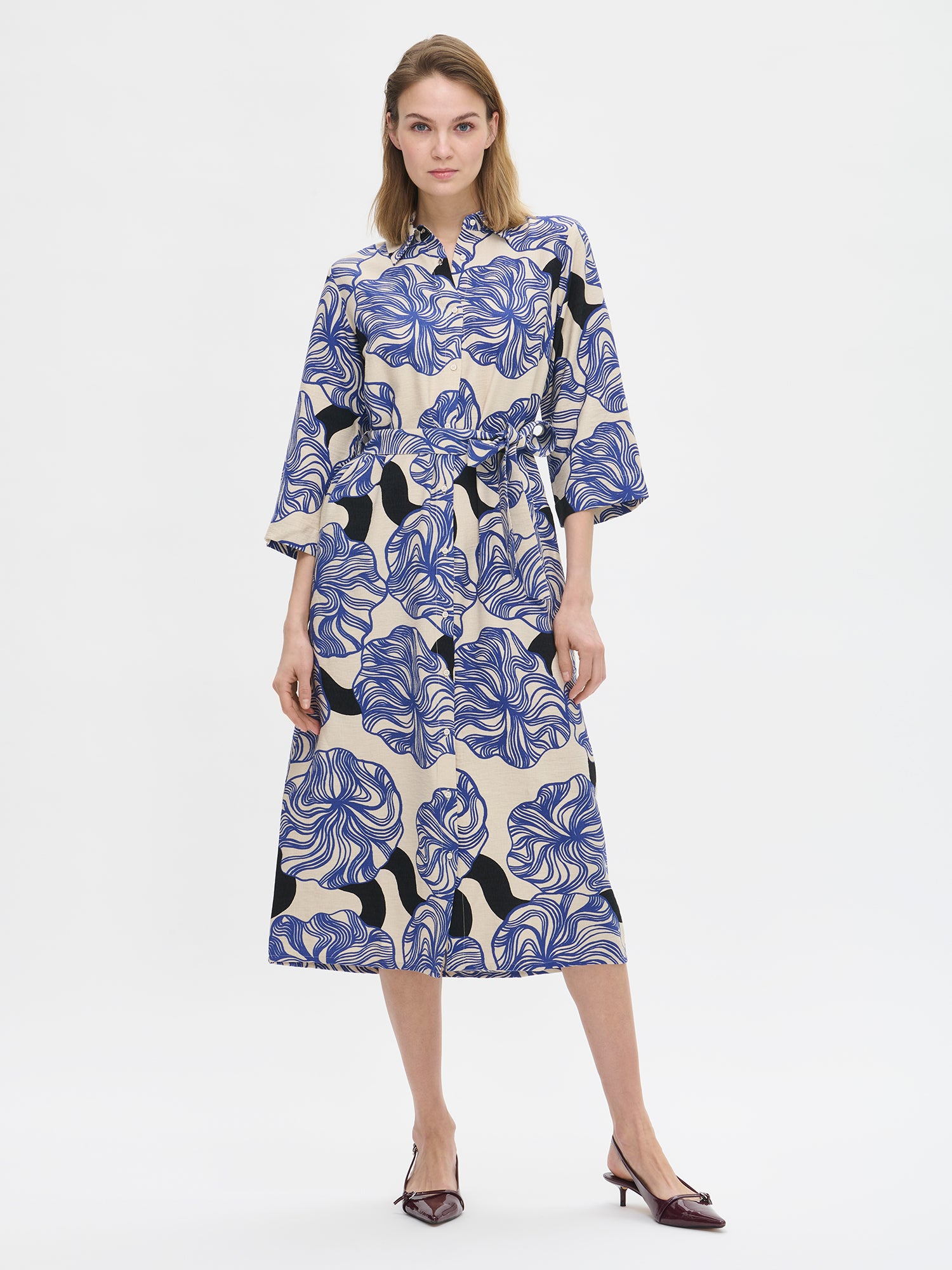 Naisten Kosmo-mekossa yhdistyy pelkistetty klassinen malli ja näyttävä sinisävyinen kuosi. Mekon istuvuus on helppo säätää sopivaksi vyöllä ja siinä on myös käytännölliset taskut. Kuvassa mallin päällä korkokenkien kanssa.