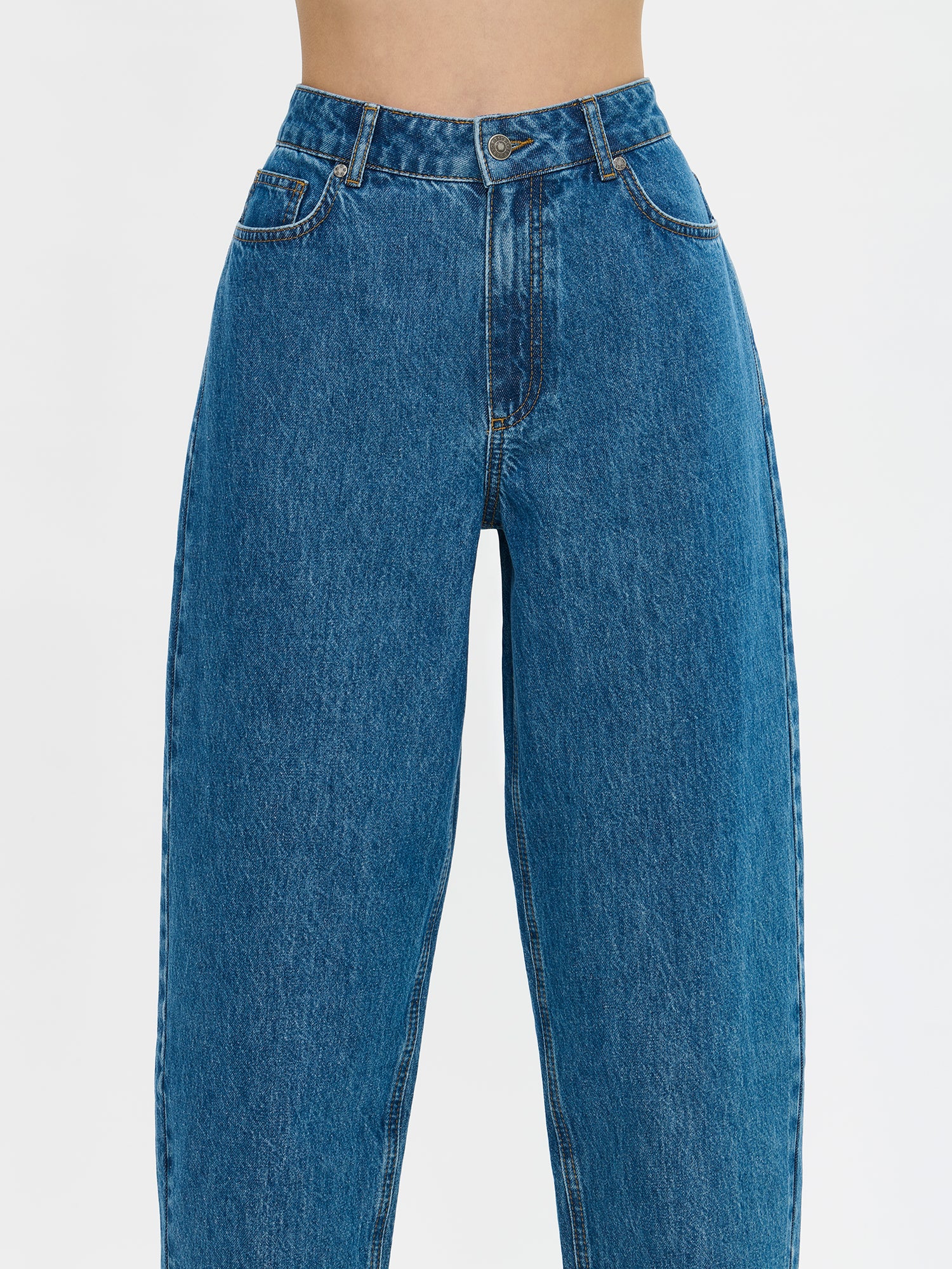 Nanson naisten barrel leg- tyyliset väljät siniset Rento-farkut. Farkuissa on normaalikorkuinen vyötärö, edessä vetoketju ja nappikiinnitys. Lahkeet ovat väljät ja kapenevat hieman kohti lahkeensuuta. Mallin päällä läheltä edestä kuvattuna.