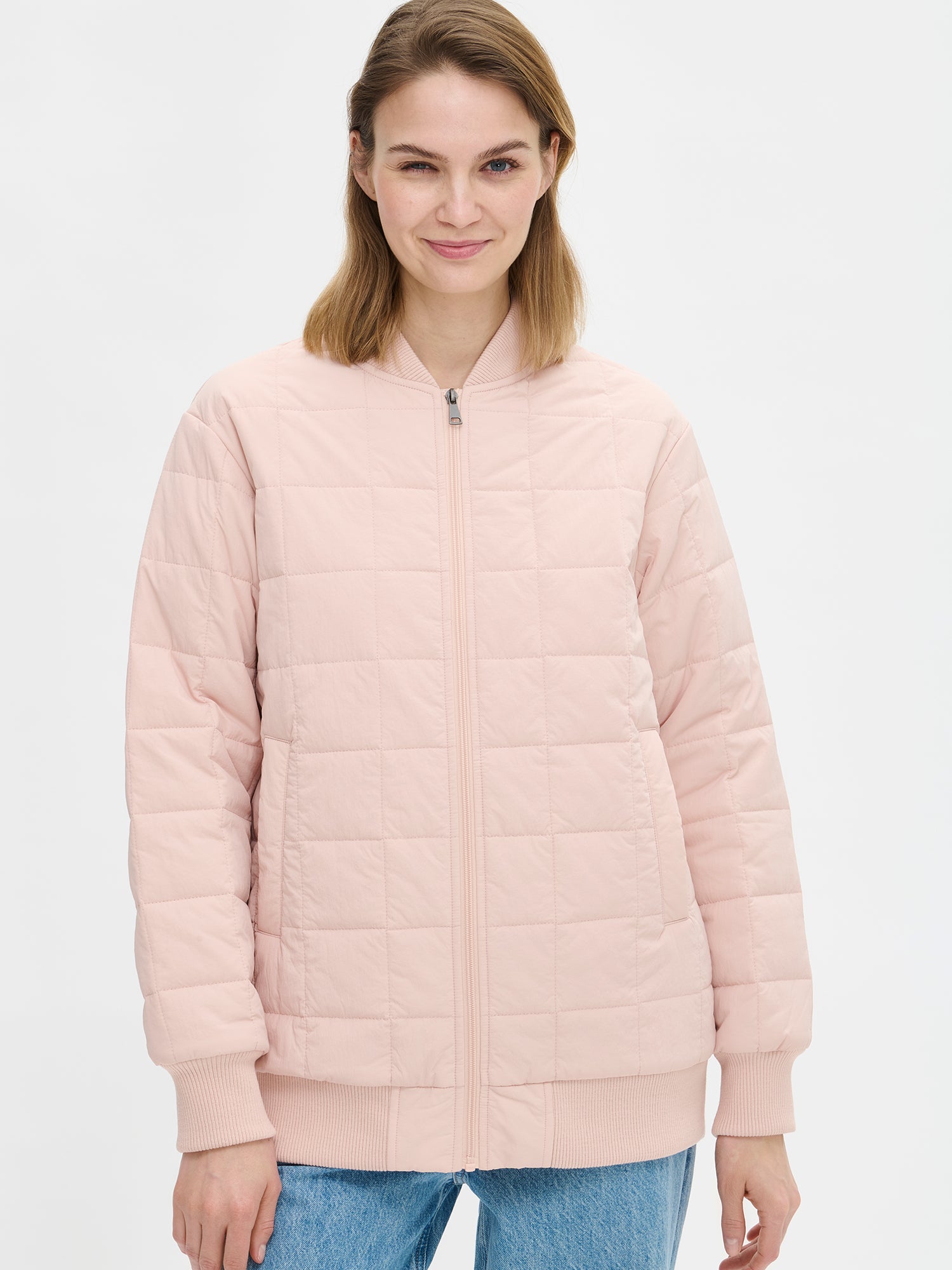 Nanson naisten rento Merje bomber tikkitakki kevyellä vanulla. Takin pääntiellä, hihansuissa ja helmassa on neulosresori. Edessä on vetoketju ja taskut. Takin olkalinja on pudotettu. Mallin päällä auki farkkujen kanssa kuvattuna läheltä.