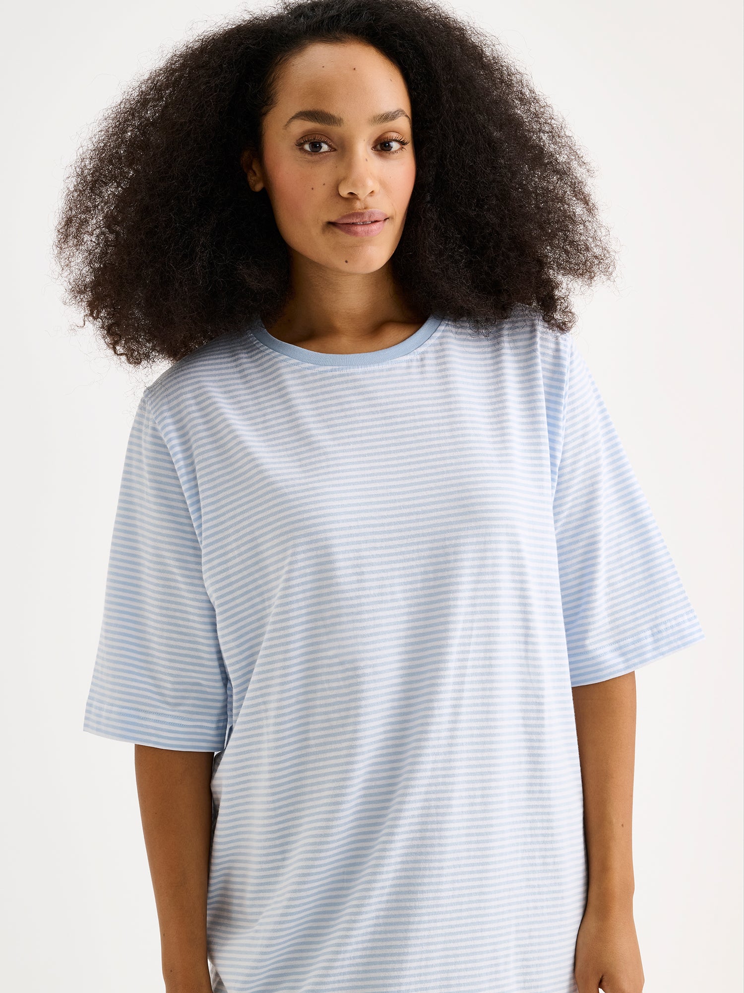 Naisten raikkaan sininen raidallinen Tyyni-yöpaita mallin päällä lähikuvassa