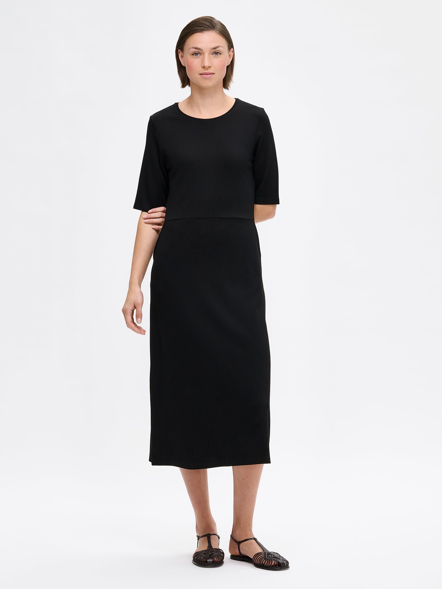 Naisten yksinkertaisen tyylikäs ja ajaton Roma-mekko mallin päällä sandaalien kanssa.