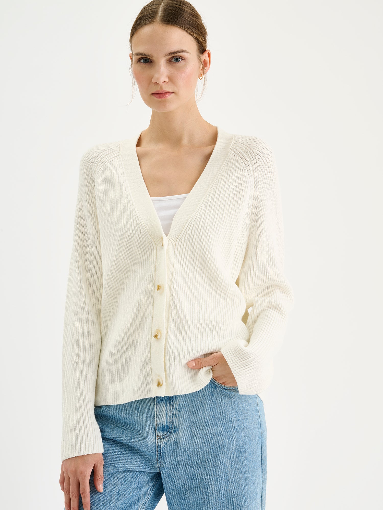 Naisten tyylikäs ja monikäyttöinen Kaveri-neuletakki pehmeän luonnonvalkoisessa sävyssä mallin päällä lähikuvassa.