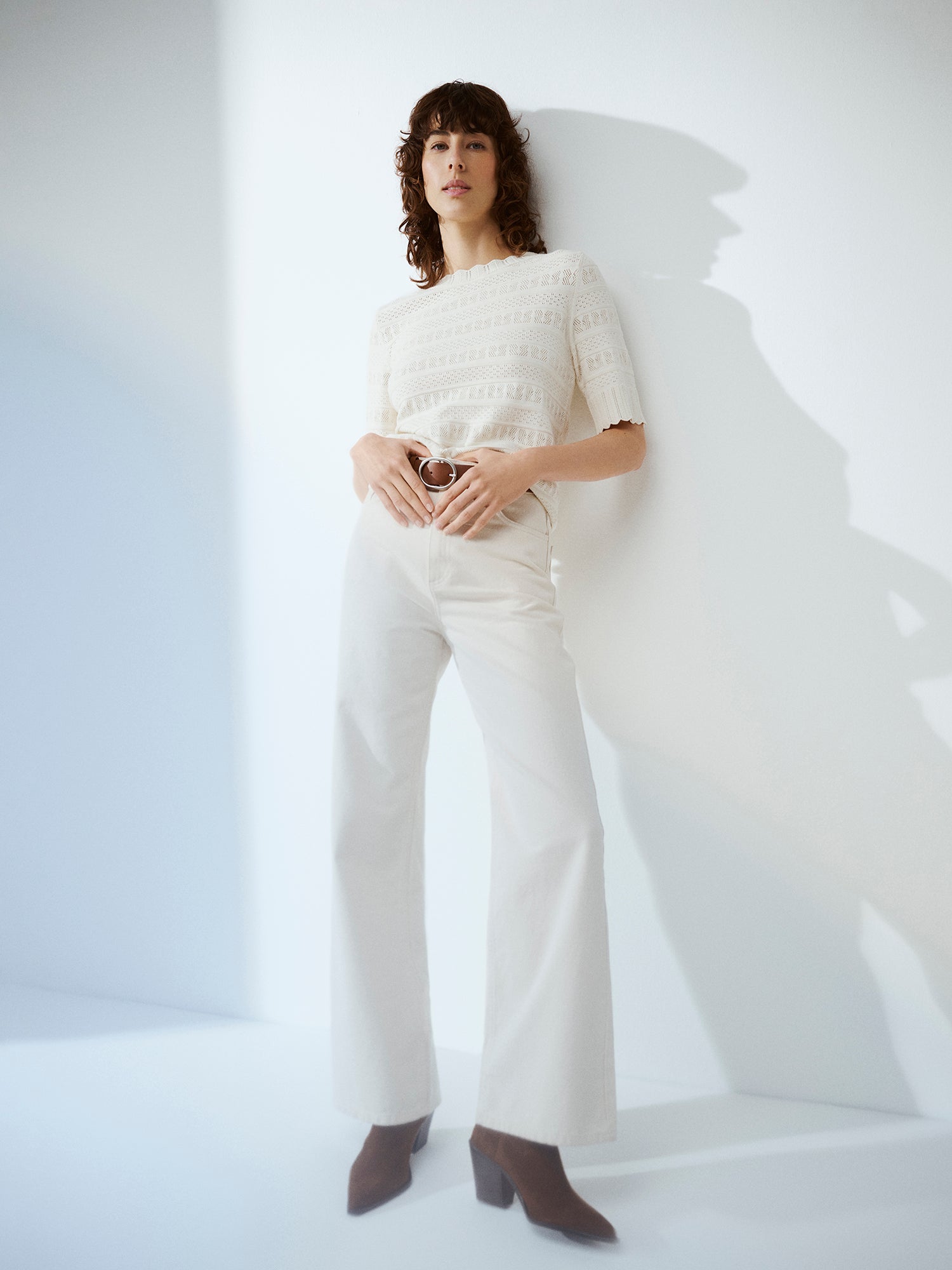 Nanson naisten valkoinen Koru-neulepaita puolipitkillä hihoilla pitsineuloksesta mallin päällä vaaleiden farkkujen kanssa.