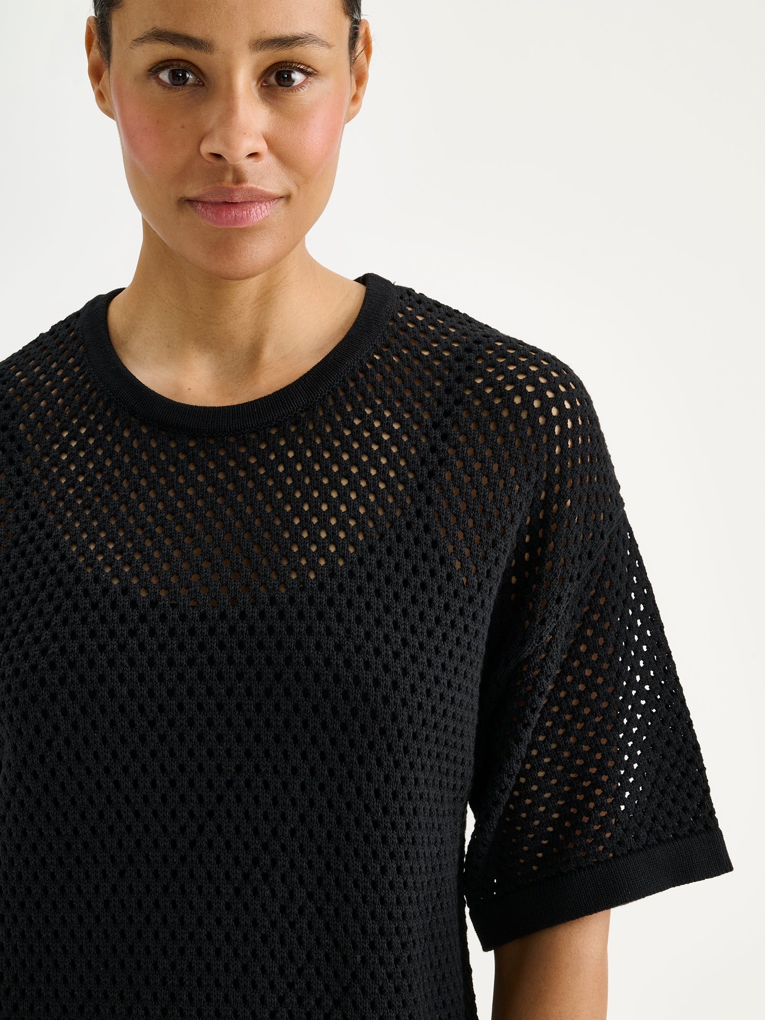 Nanson naisten trendikäs musta Aure -reikäneulemekko mallin päällä lähikuvassa.