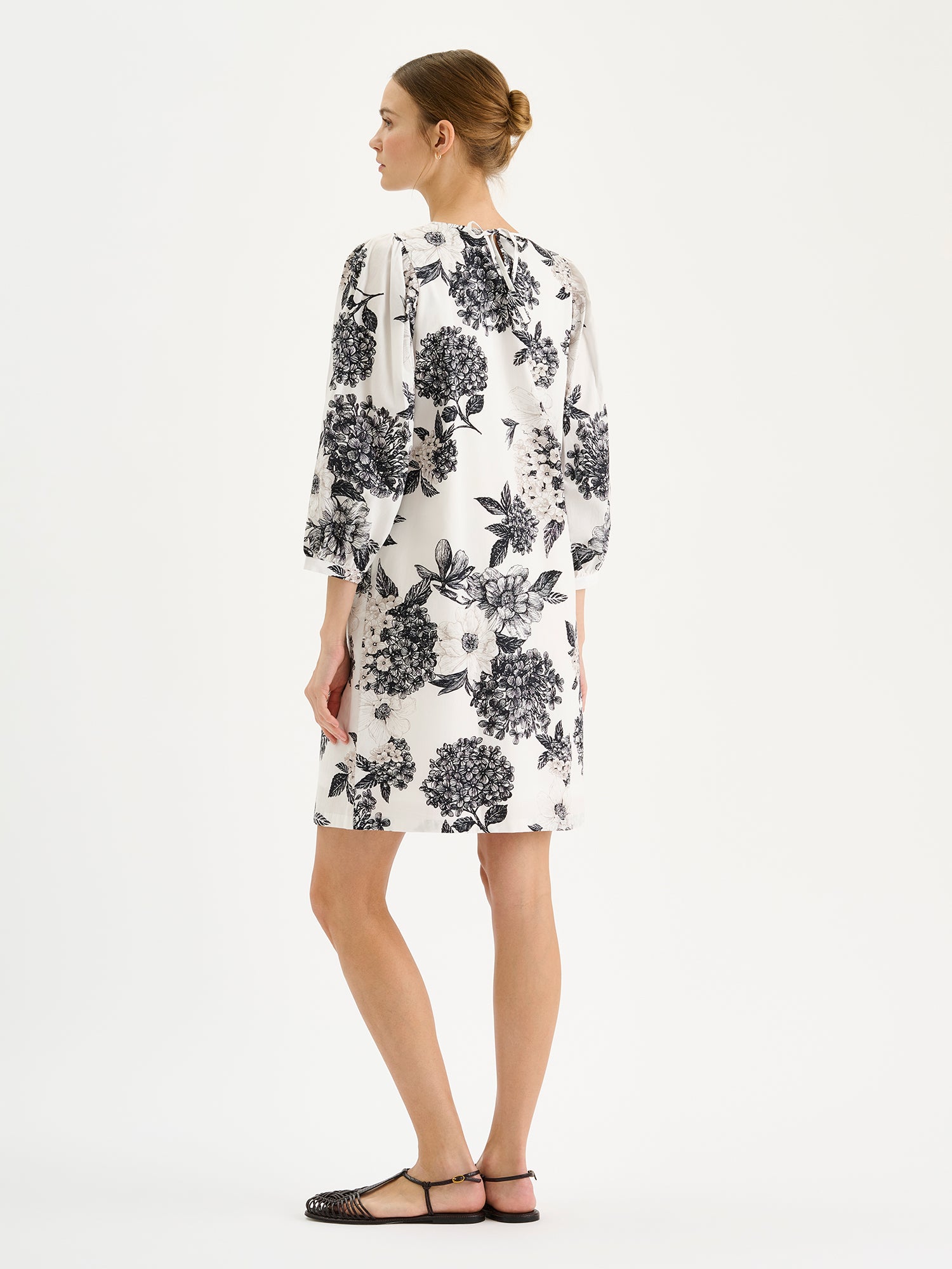 Naisten hurmaava mustavalkoinen kuosillinen Palatsi-mekko mallin päällä sandaalien kanssa takaa kuvattuna.