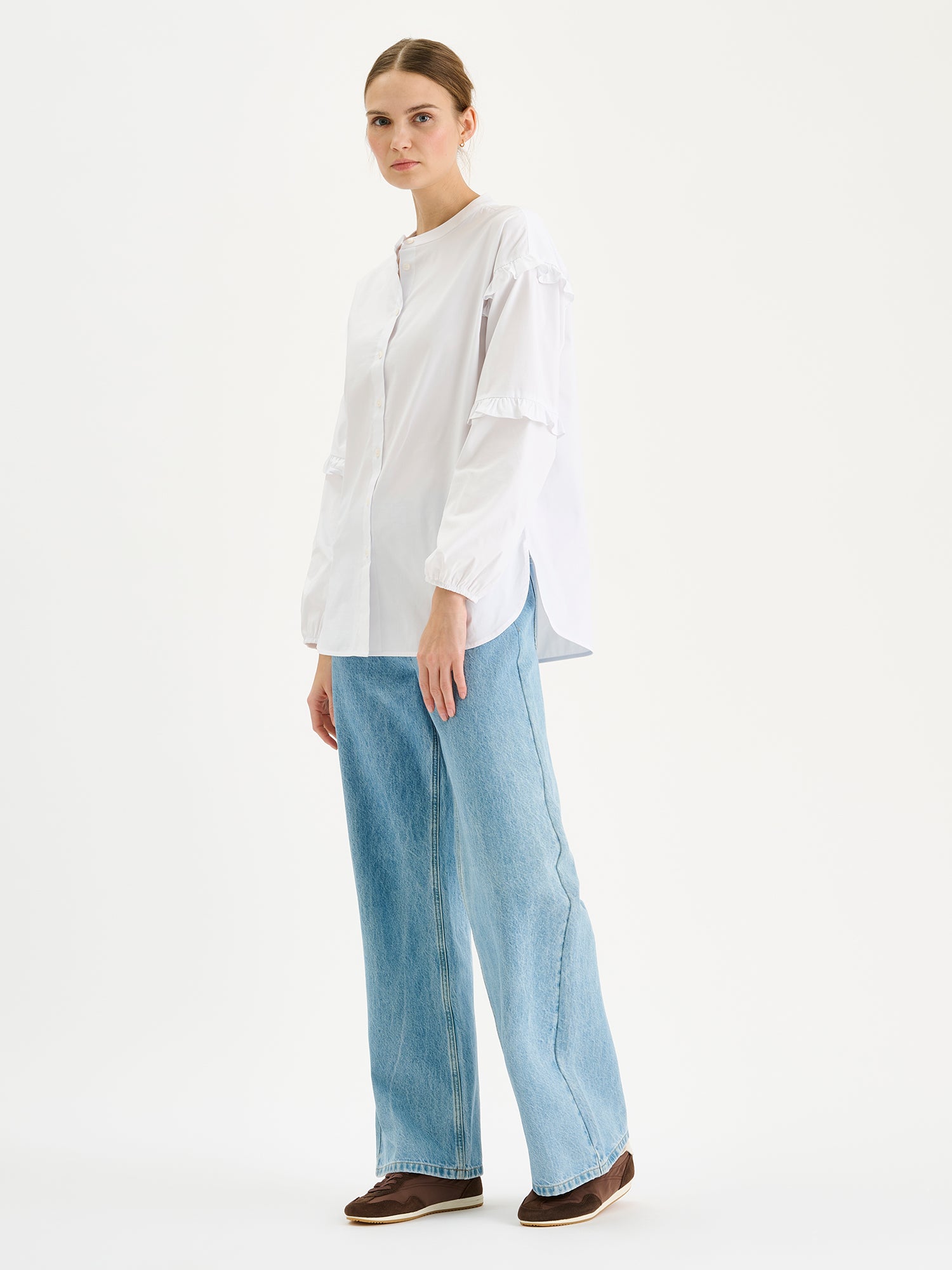 Naisten raikas valkoinen Katri-paitapusero, jossa on kauniit frillayksityiskohdat hihoissa. Kuvassa mallin päällä farkkujen kanssa.