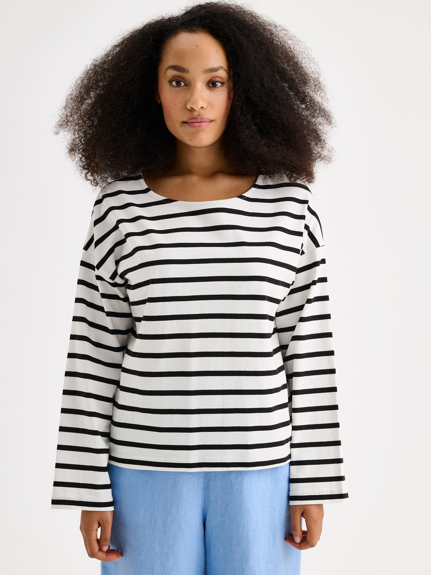 Naisten mustavalko-raidallinen ja ihanan rennon mallinen Breton-pusero mallin päällä pellavahousujen kanssa lähikuvassa.