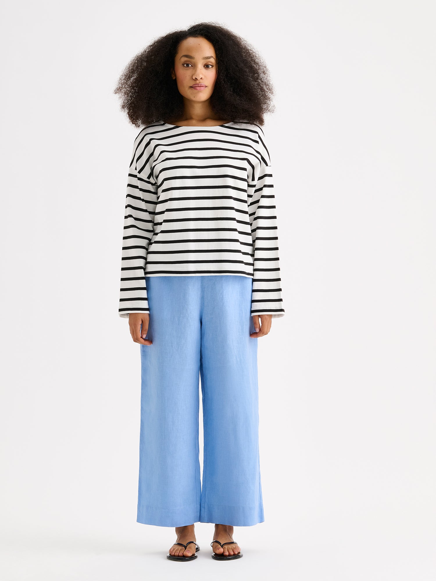 Naisten mustavalko-raidallinen ja ihanan rennon mallinen Breton-pusero mallin päällä pellavahousujen kanssa.