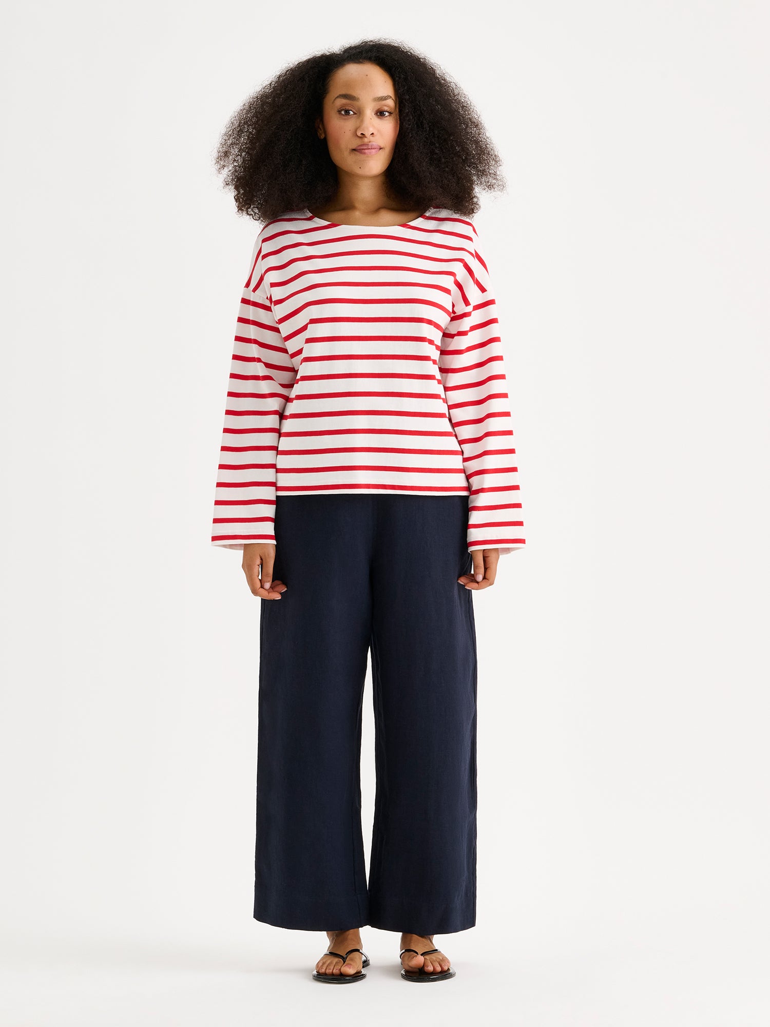 Naisten puna-valko-raidallinen ja ihanan rennon mallinen Breton-pusero mallin päällä pellavahousujen kanssa.