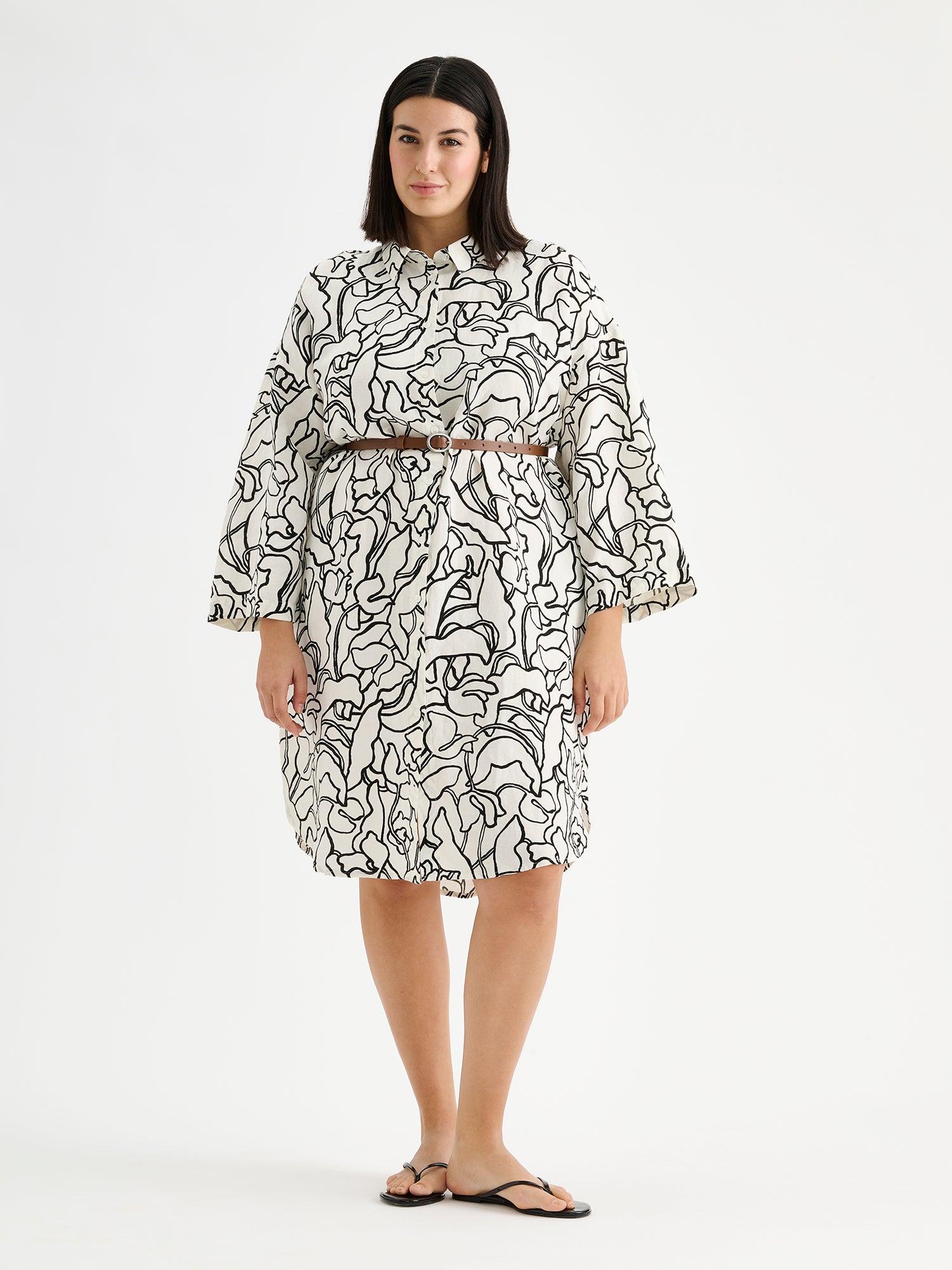 Naisten mukavan rento Iiris-paitamekko, jossa on tyylikäs ja näyttävä mustavalkoinen kukkakuosi mallin päällä sandaalien ja vyön kanssa.