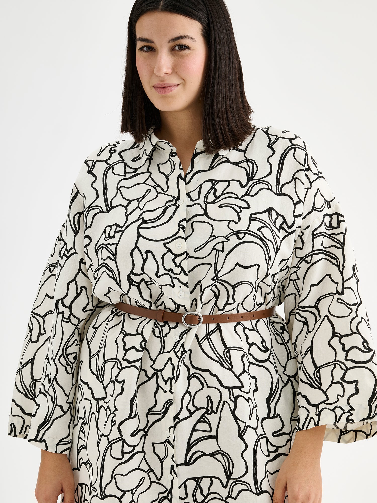 Naisten mukavan rento Iiris-paitamekko, jossa on tyylikäs ja näyttävä mustavalkoinen kukkakuosi mallin päällä vyön kanssa lähikuvassa.