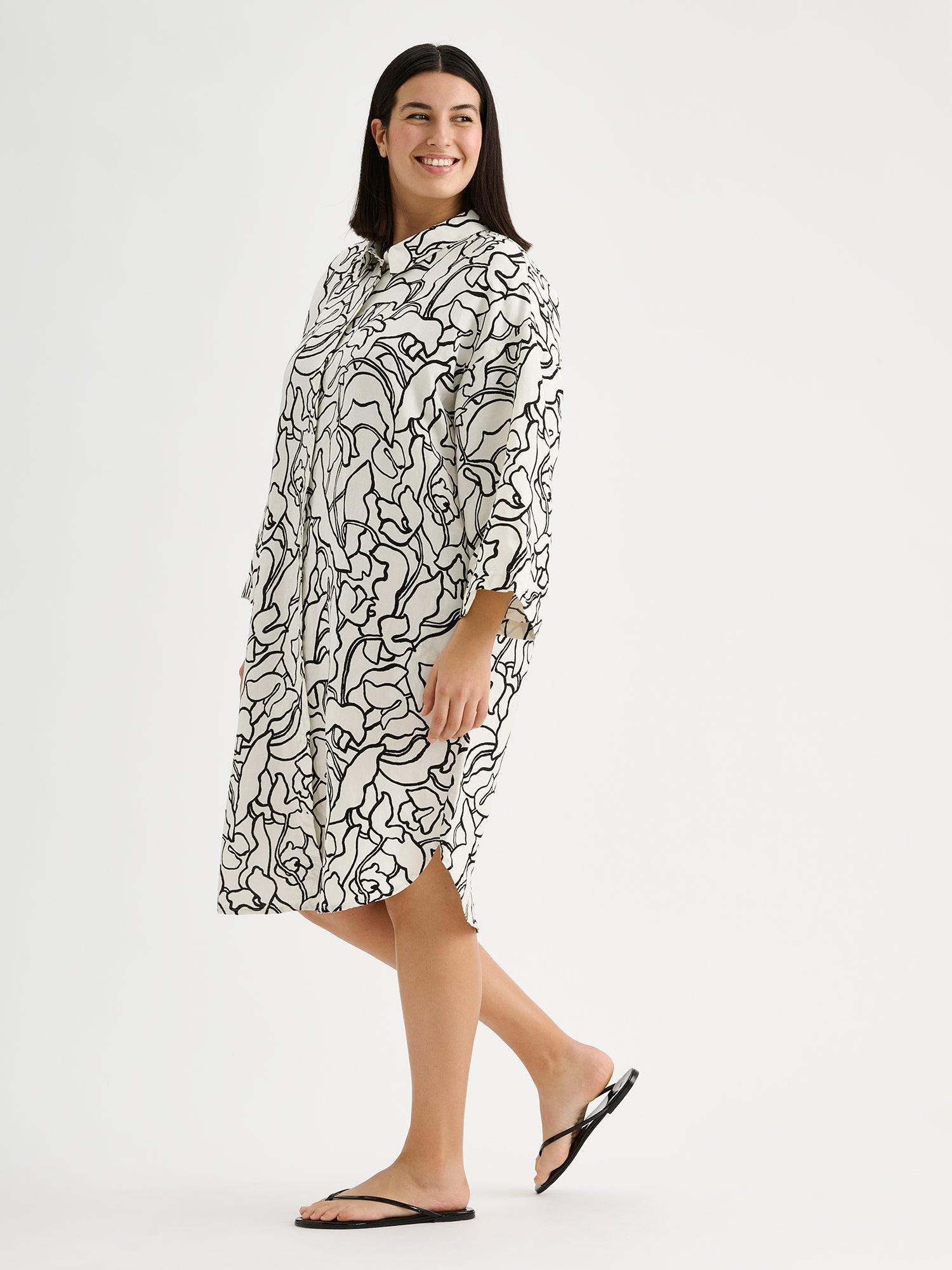 Naisten mukavan rento Iiris-paitamekko, jossa on tyylikäs ja näyttävä mustavalkoinen kukkakuosi mallin päällä sandaalien kanssa.