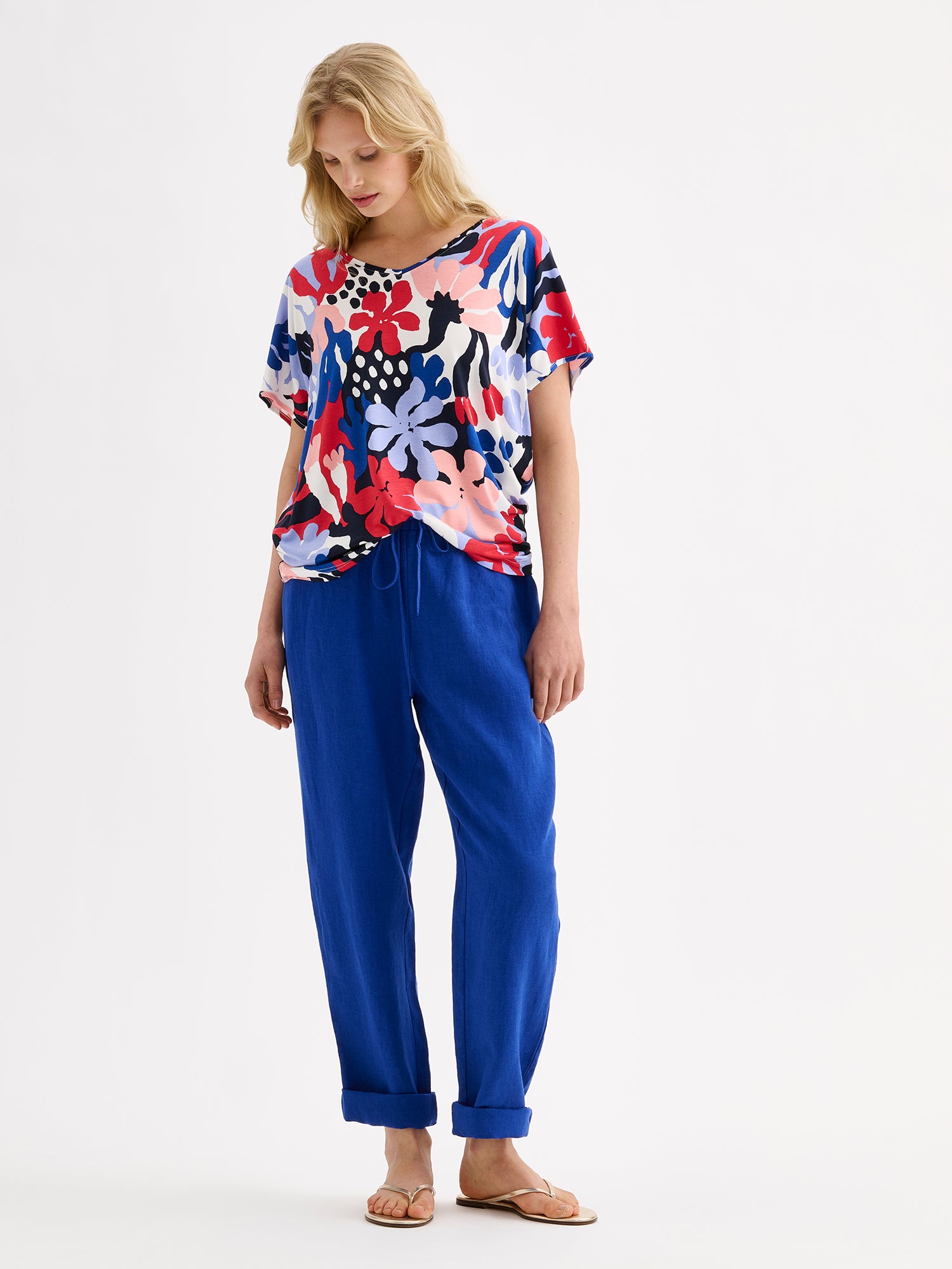 Nanson naisten laadukas ja mukava Koralli-trikoopusero, jossa on raikkaan värikäs kuosi mallin päällä sinisten pellavahousujen kanssa.