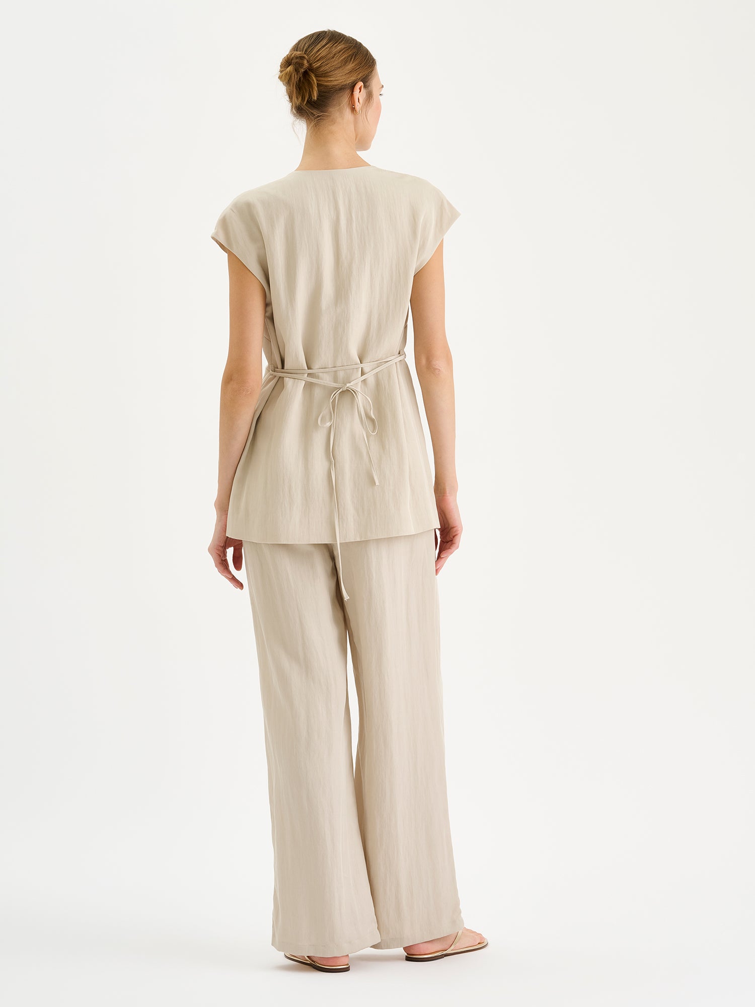 Nanson naisten tyylikäs beige Nizza-liivi ja Nizza -housut mallin päällä kuvattuna takaa.