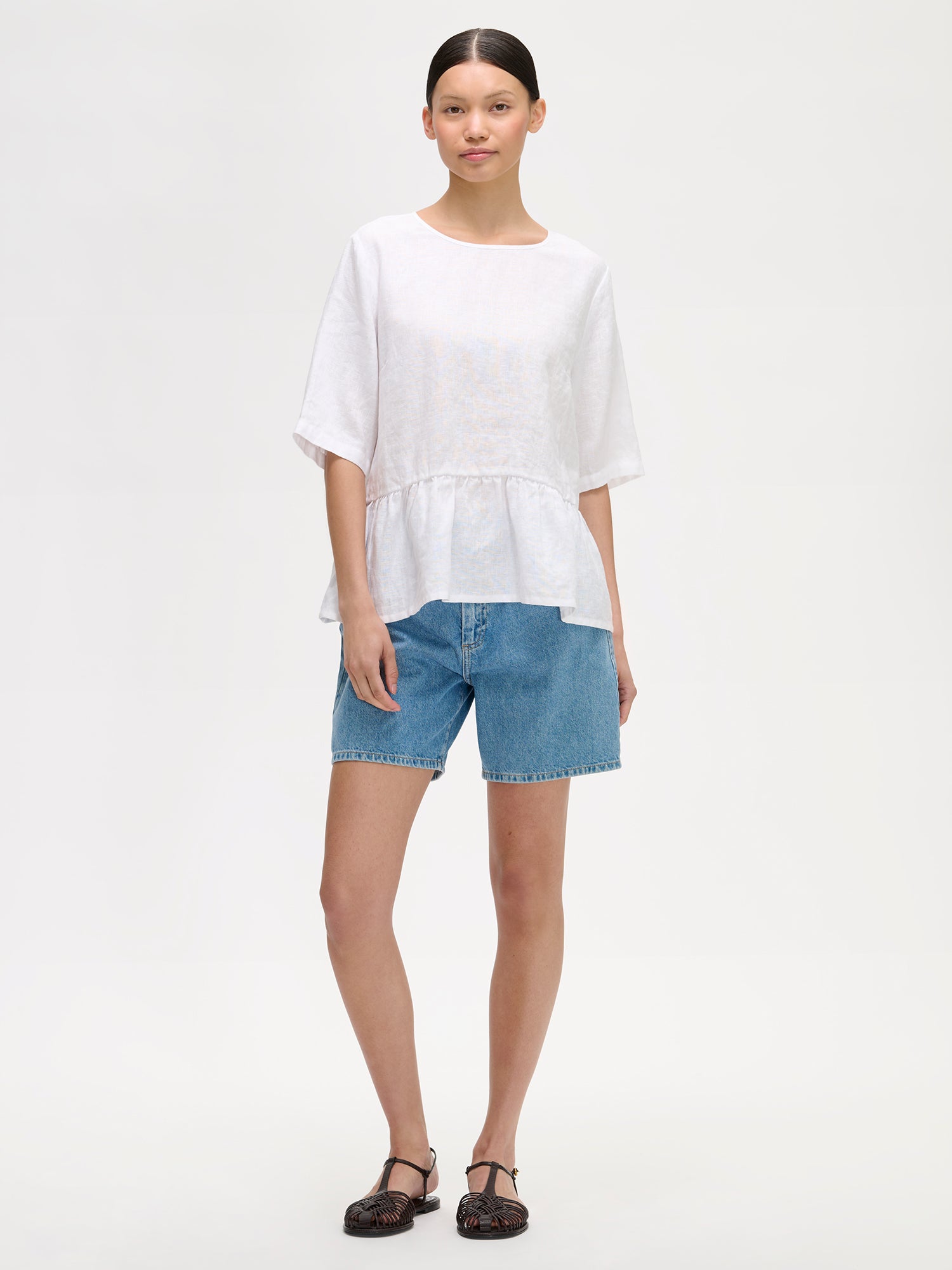 Nanson naisten kaunis ja ihanan rennon mallinen valkoinen Liisu-pellavapusero, jonka helmassa on viehättävä frilla, mallin päällä farkkushortsien kanssa.