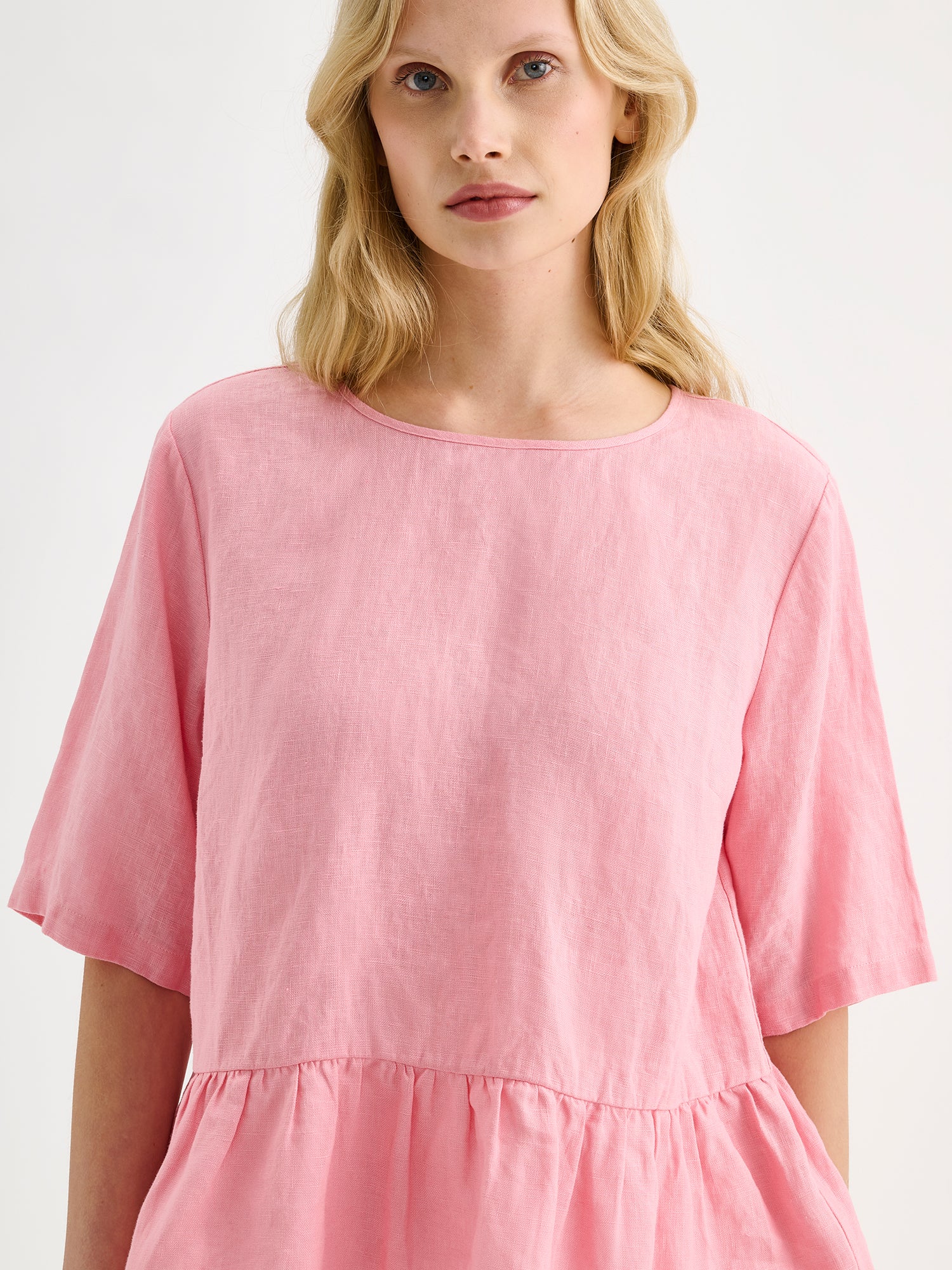 Nanson naisten kaunis ja ihanan rennon mallinen vaaleanpunainen Liisu-pellavapusero, jonka helmassa on viehättävä frilla, mallin päällä lähikuvassa.