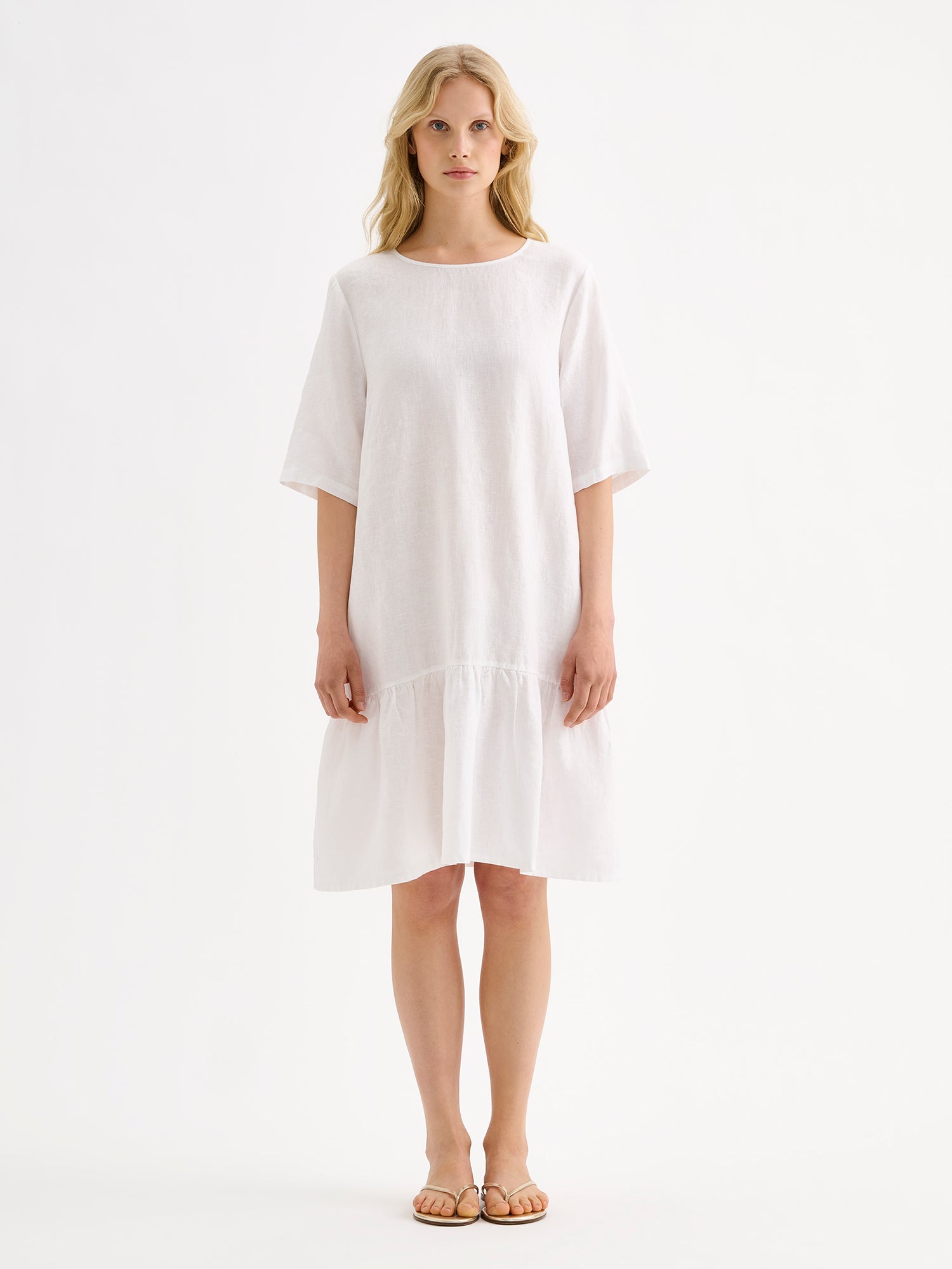 Nanson naisten kaunis ja ihanan rennon mallinen valkoinen Liisu-pellavamekko, jonka helmassa on runsas frilla, mallin päällä sandaalien kanssa.