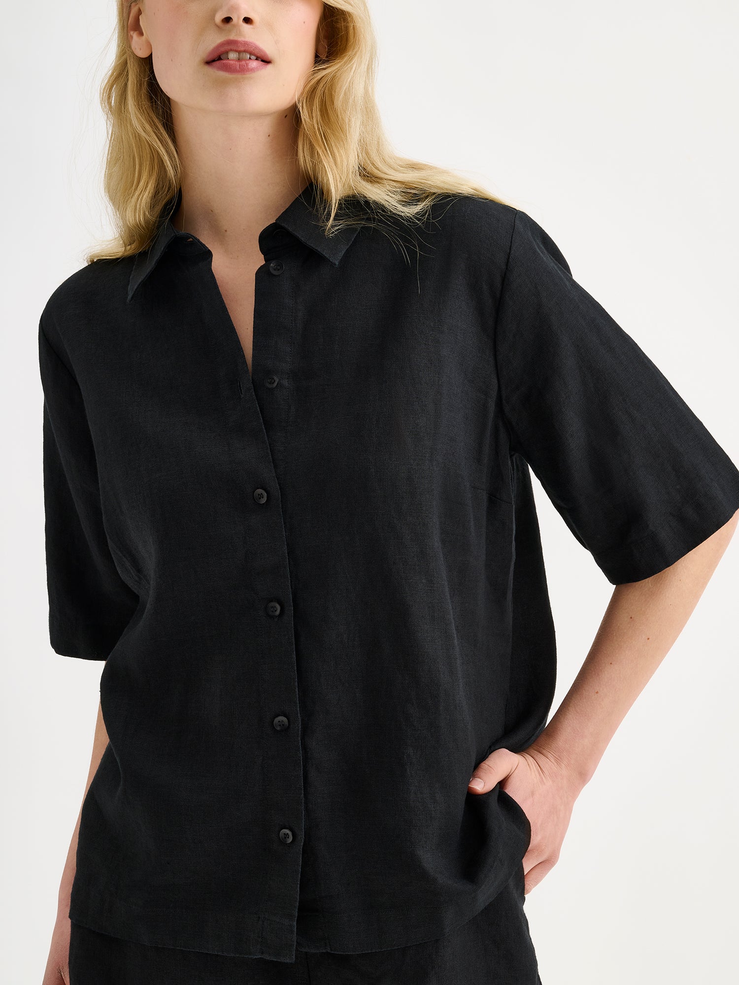 Naisten rento musta Liine-paitapusero, joka on valmistettu hengittävästä pellavasta mallin päällä pellavashortsien kanssa, lähikuvassa.