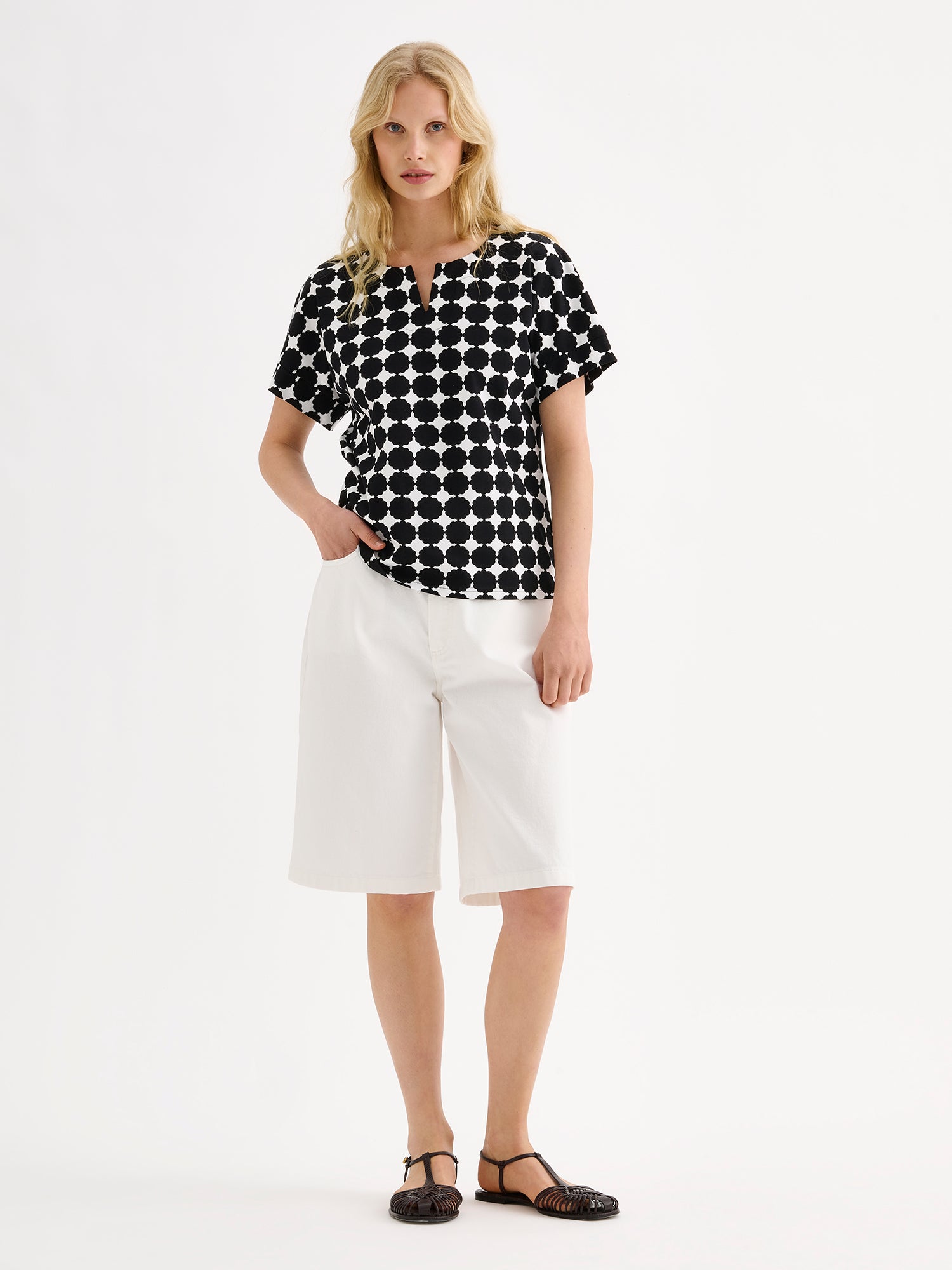 Nanson naisten tyylikäs kuosillinen mustavalkoinen Avene-trikoopusero mallin päällä valkoisten shortsien kanssa.