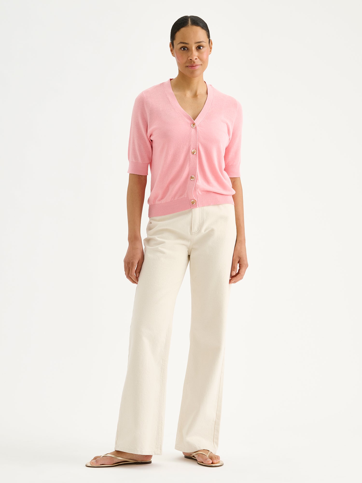 Nanson naisten vaaleanpunainen lyhythihainen Karina-neuletakki mallin päällä vaaleiden farkkujen kanssa.