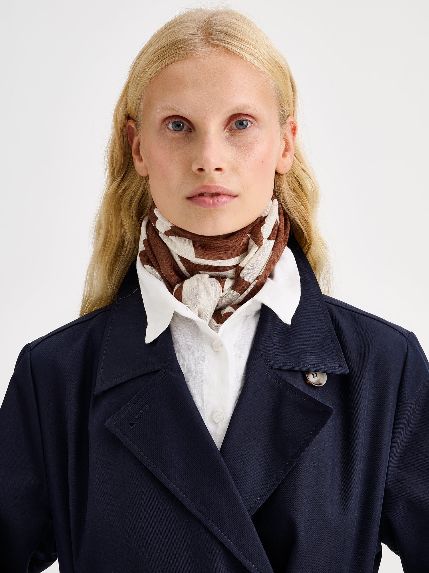 Naisten tyylikäs kuviollinen ruskea-valkoinen Palsta-huivi ihanan kevyestä ja hengittävästä viskoosi-pellava-sekoitteesta mallin päällä sinisen trenssin kanssa