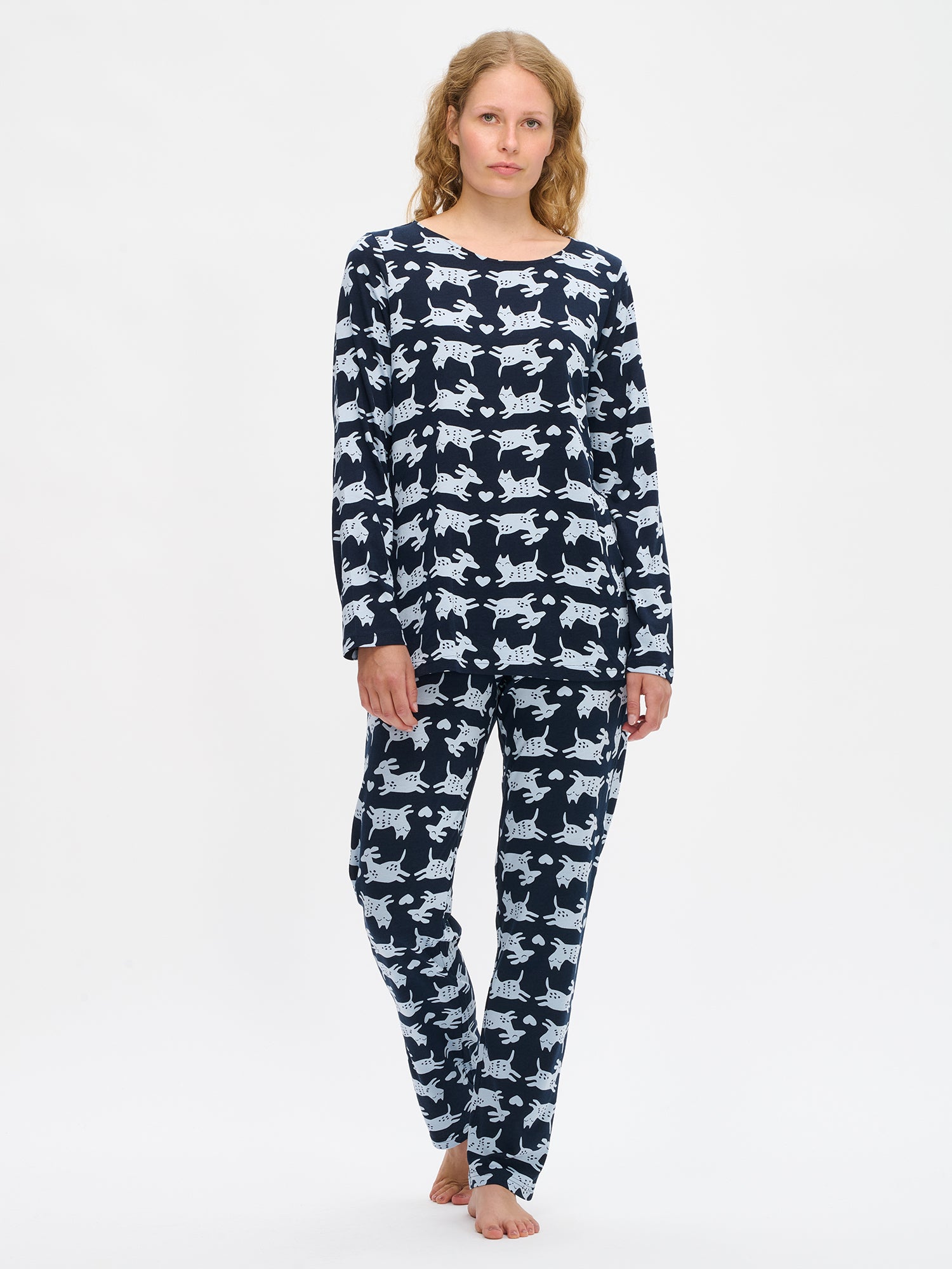 Nanson naisten tummansininen Kamu-pyjama, pitkähihainen paita ovaalilla pääntiellä ja suorat housut joustavalla vyötäröllä, mallin yllä kokokuvassa.