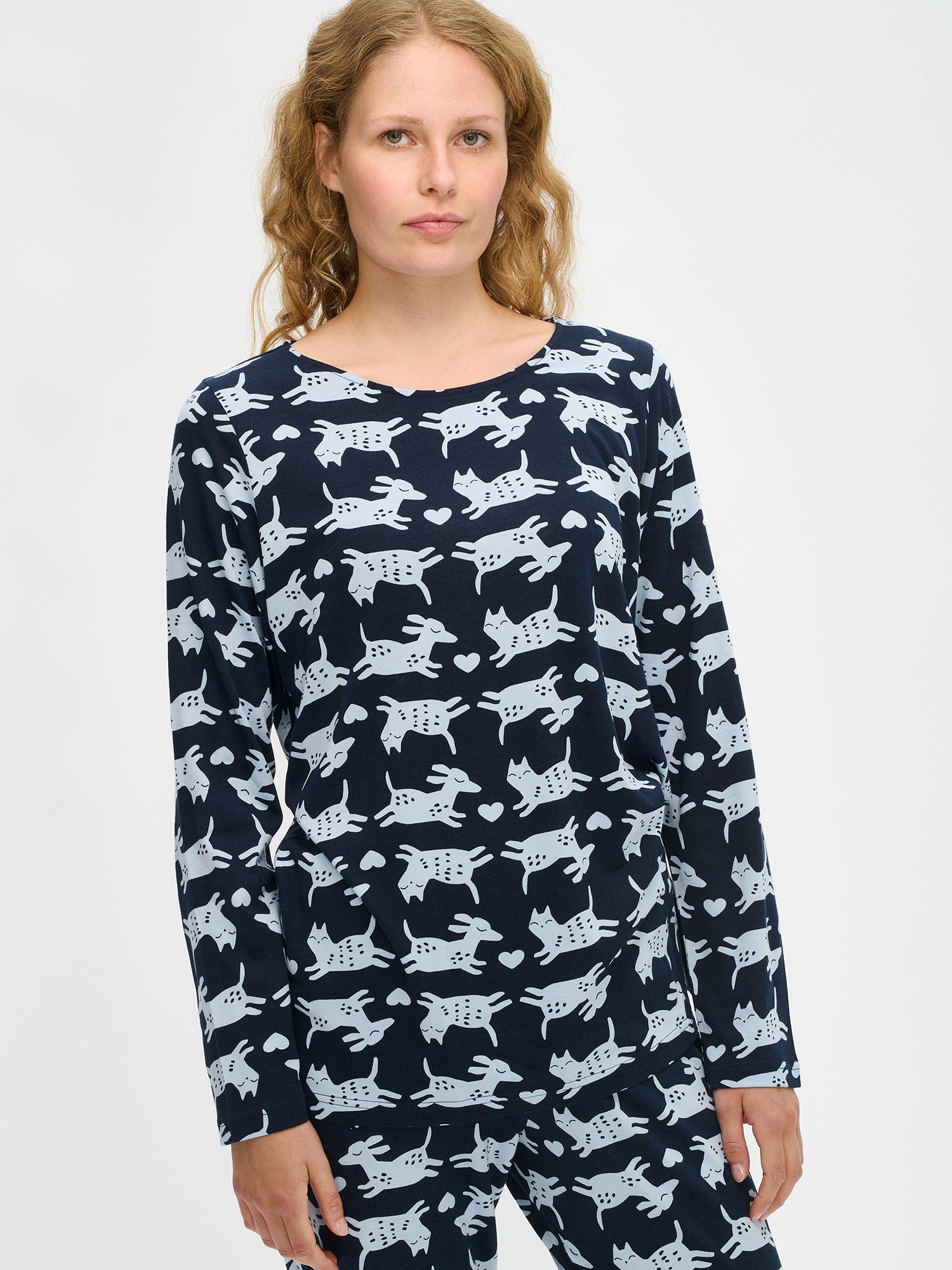 Nanson naisten tummansininen Kamu-pyjama, kuosillinen paita ja housut pehmeää puuvilla-modaalia, mallin yllä puolivartalokuvassa.