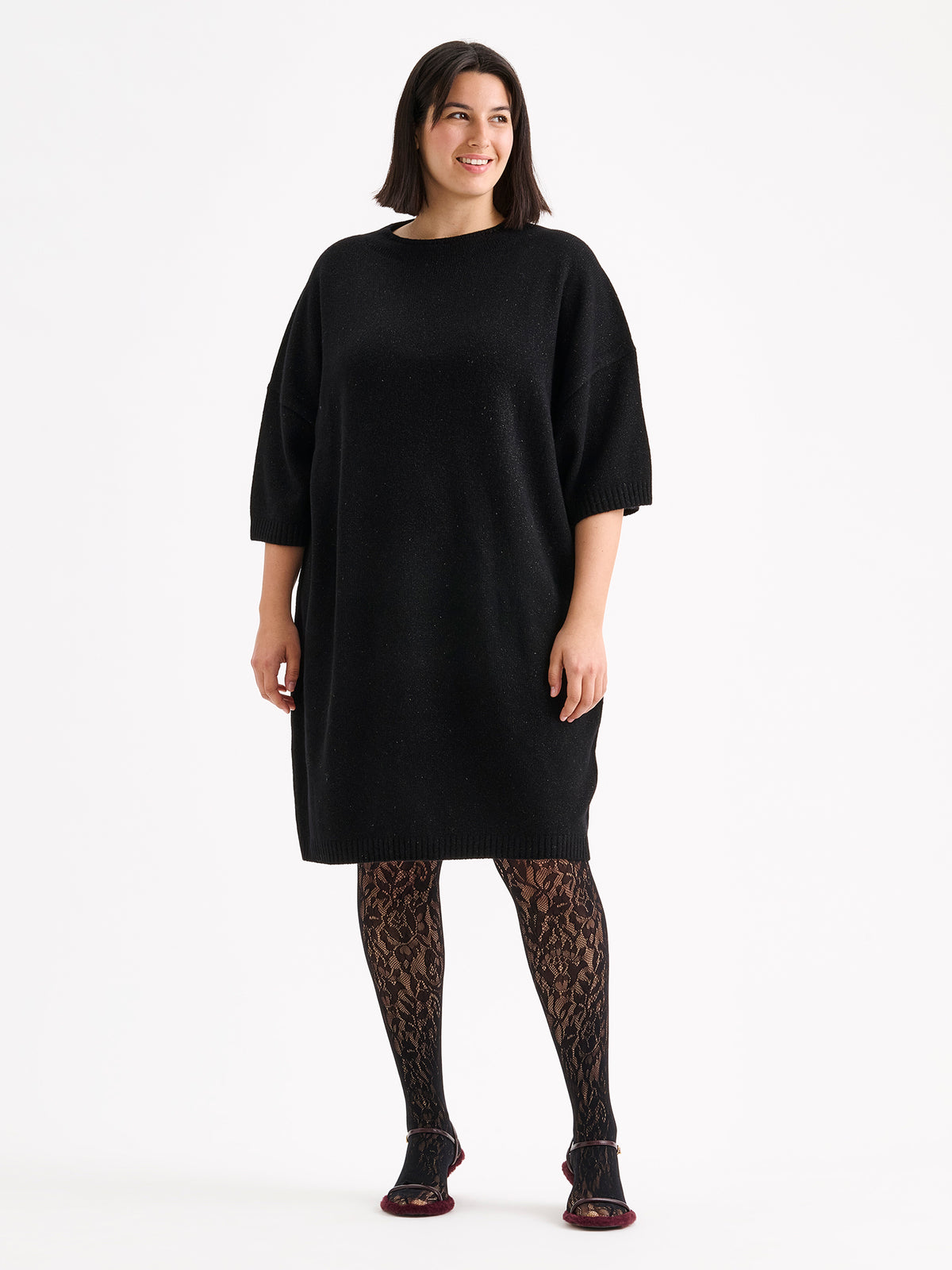 Nanson naisten rento, hieman oversized-mallinen musta kimaltava Lumine-neulemekko mallin päällä pitsisukkahousujen kanssa. | XL - 178cm